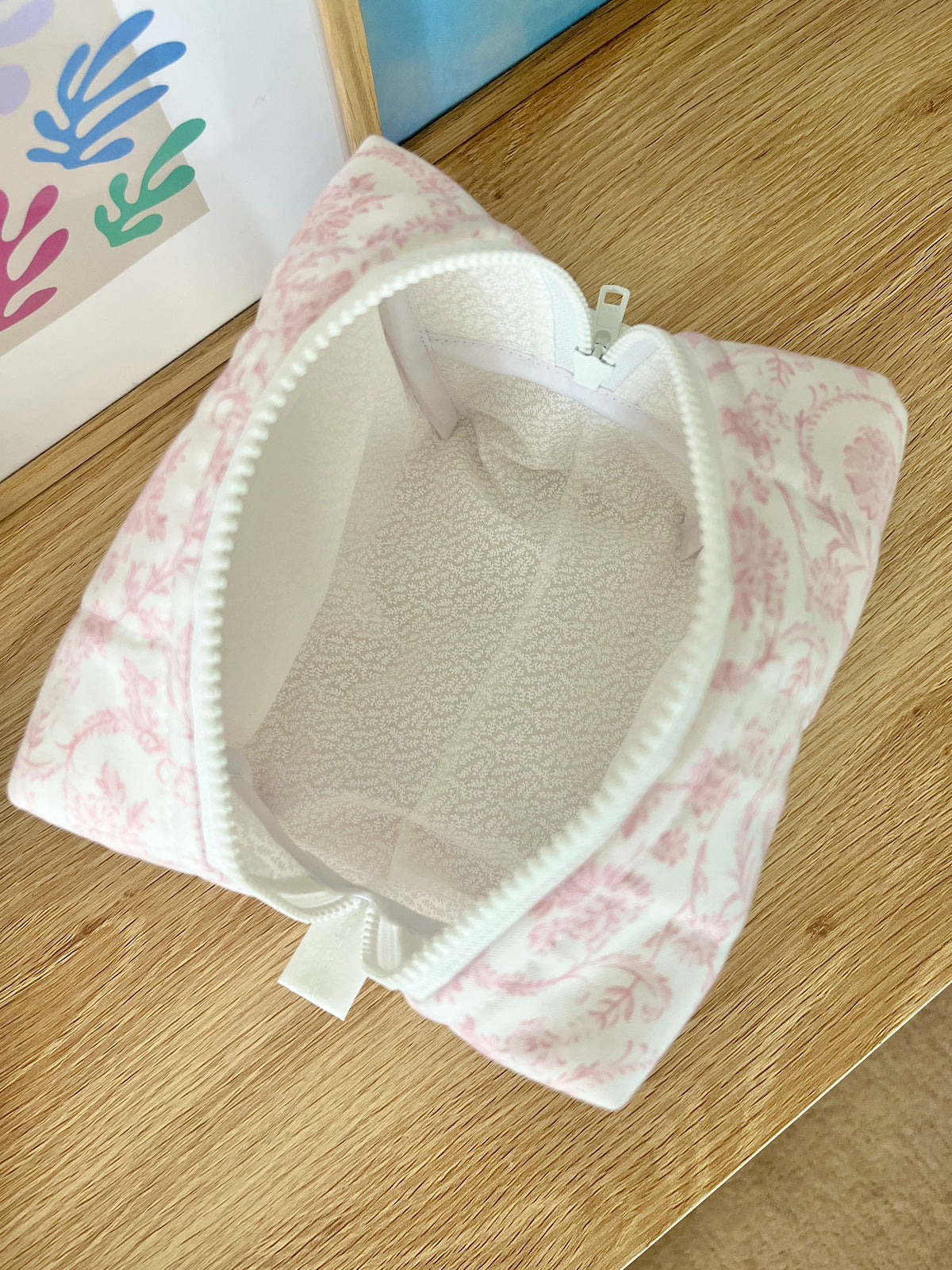 Pink floral medium makeup bag open, showing light interior lining and zipper