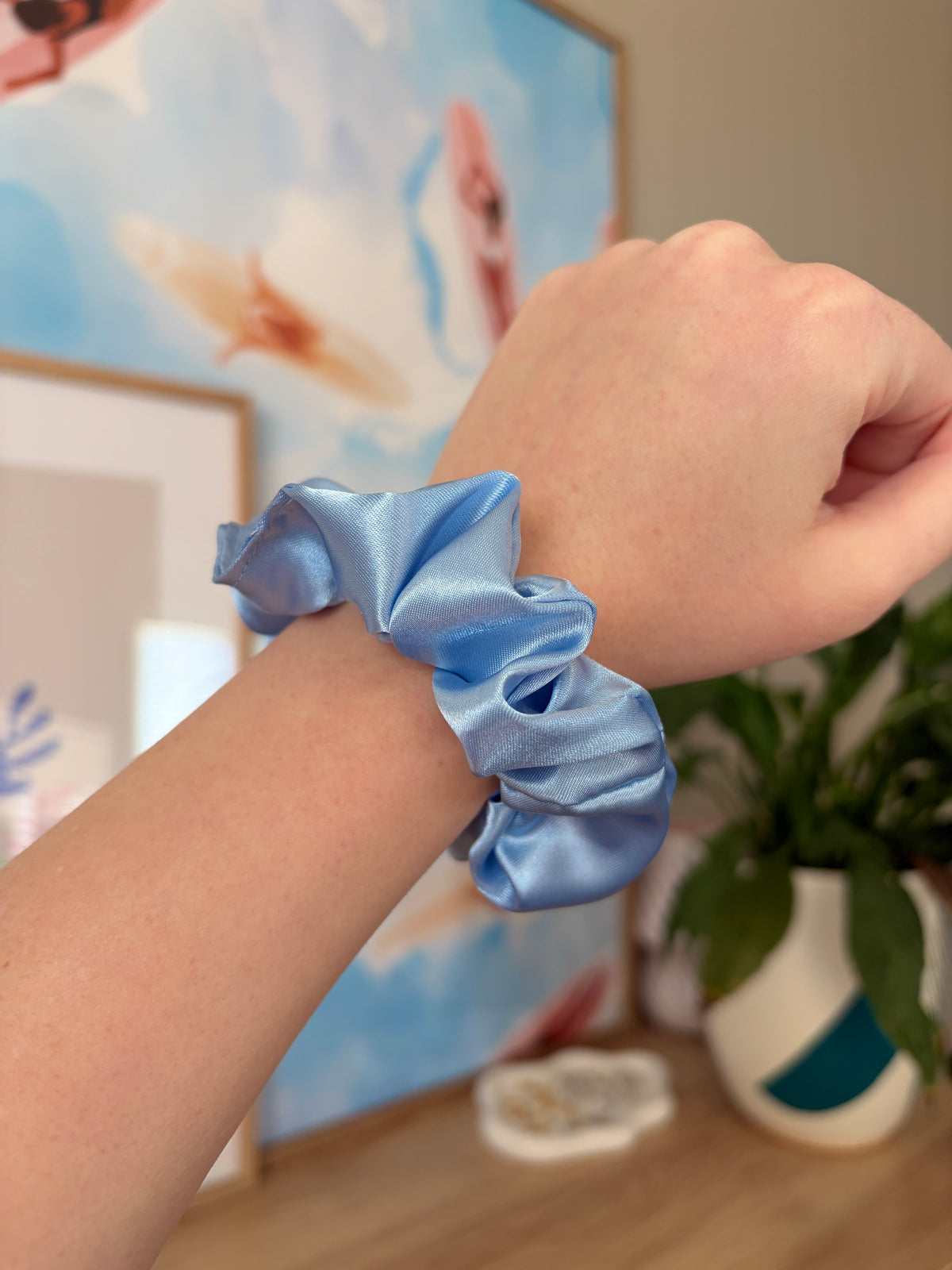 Light blue satin scrunchie on wrist, gathered ruffled band