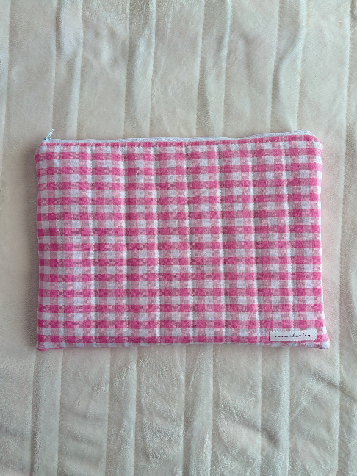 Pink gingham laptop and tablet sleeve with striped trim around the edges.