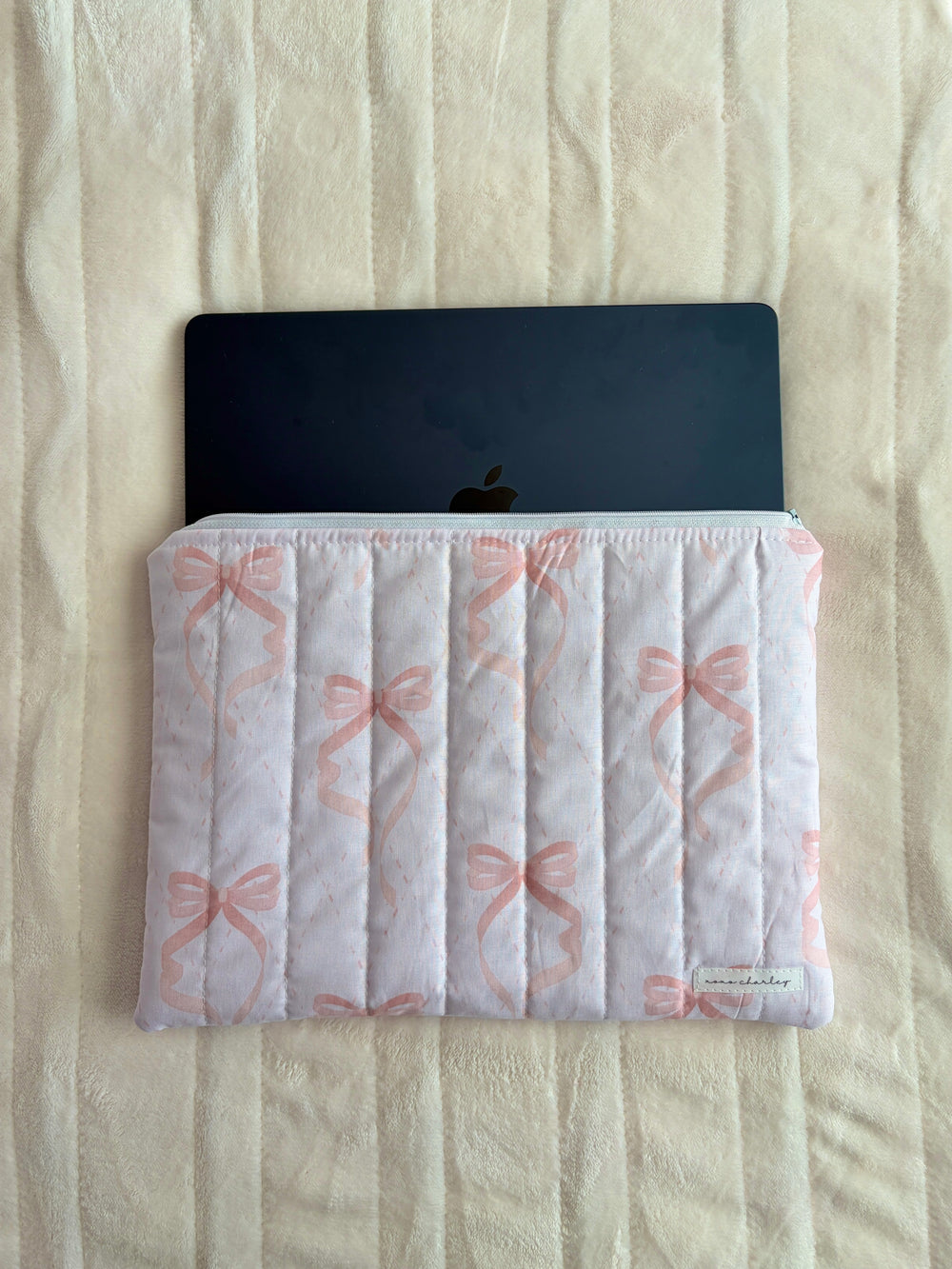 Pink bow quilted sleeve with open top holding a device