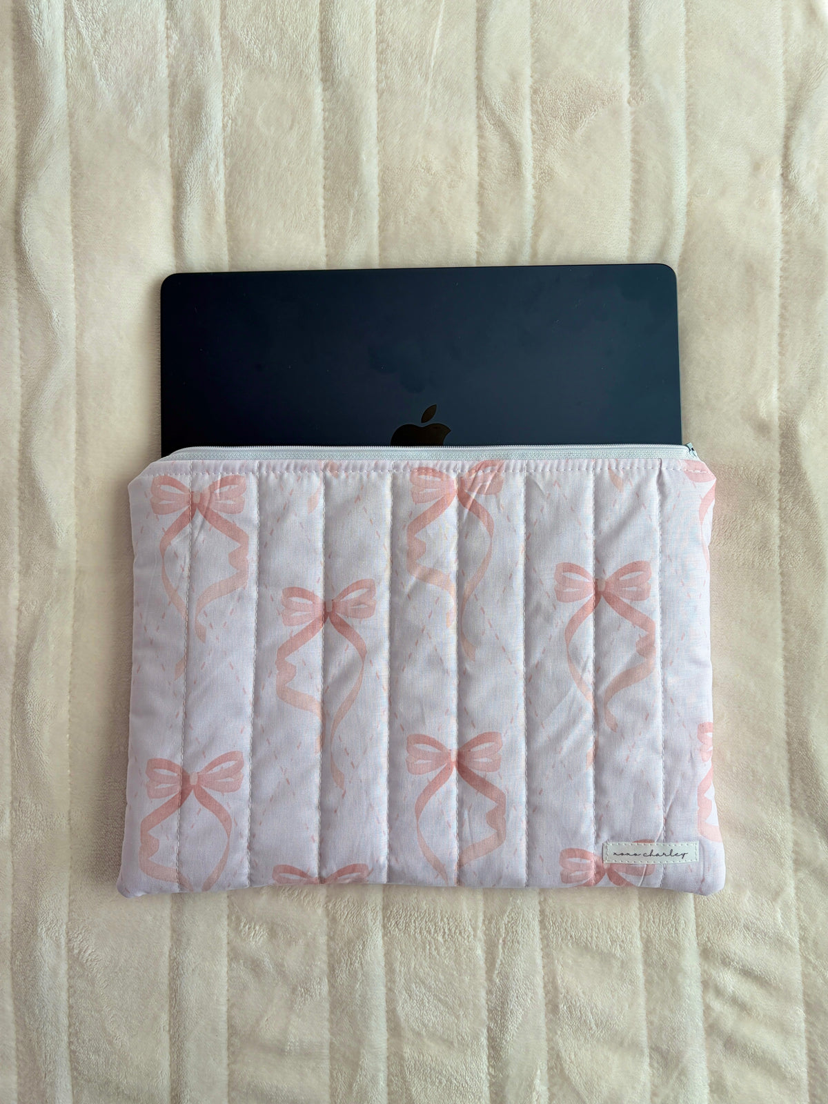 Pink bow quilted sleeve with open top holding a device