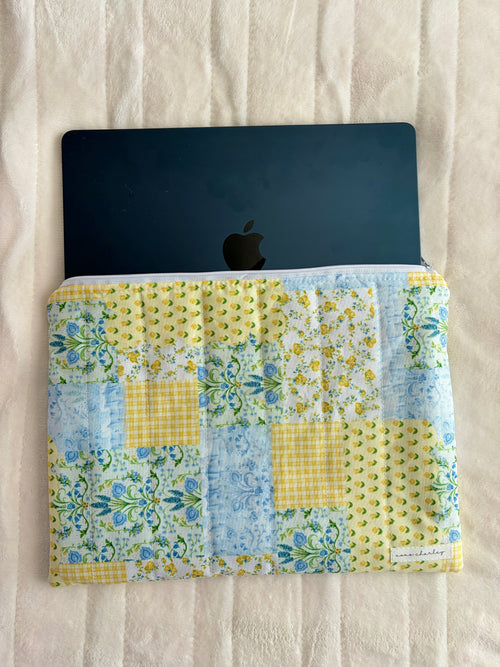 Patchwork laptop and tablet sleeve holding a dark device with the zipper top open
