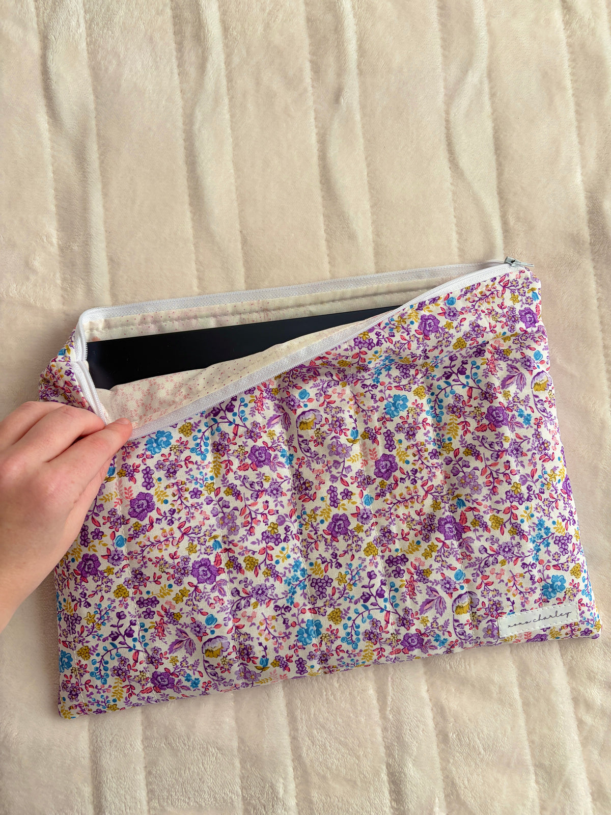Hand holding floral laptop & tablet sleeve, open zip with purple ditsy print