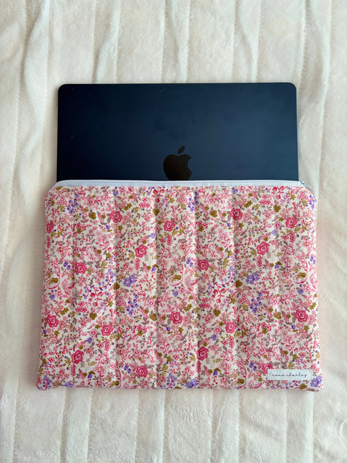 Pink floral laptop sleeve holding a laptop with Apple logo visible