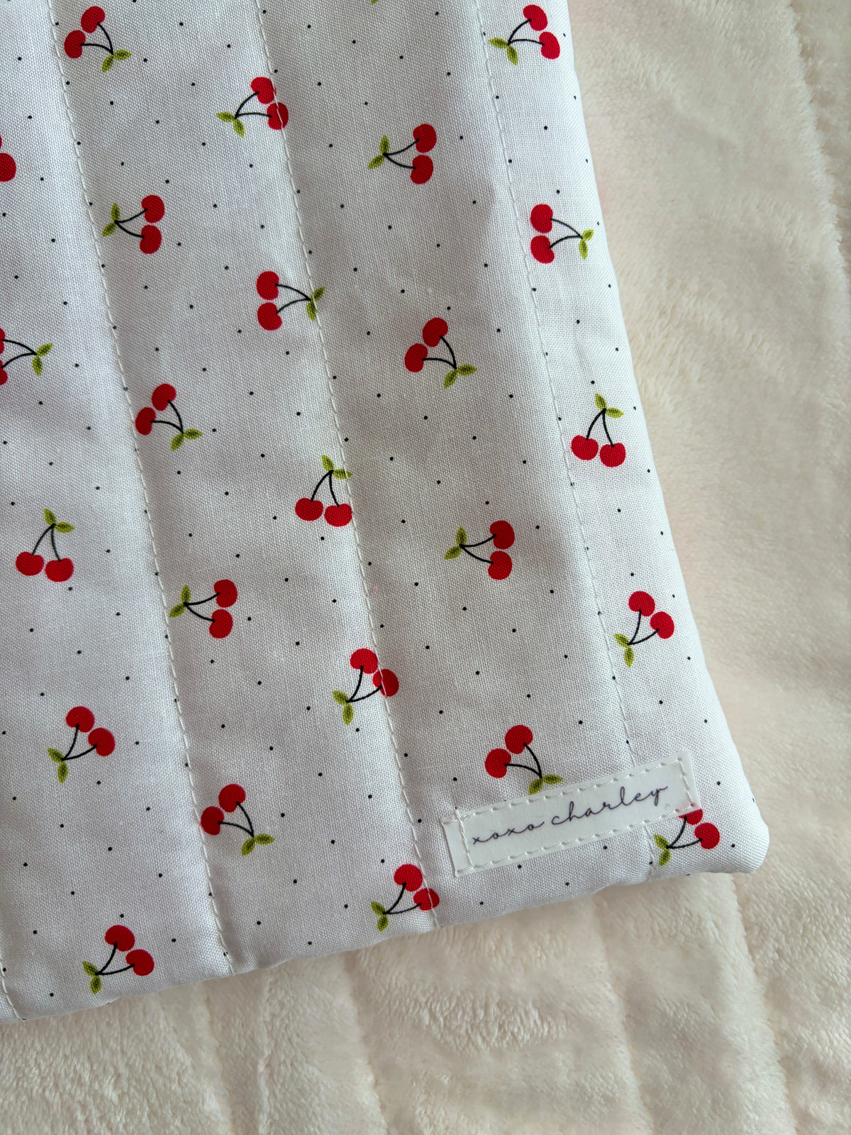 Laptop and tablet sleeve in light gray with red cherry print, stitched hem and logo patch