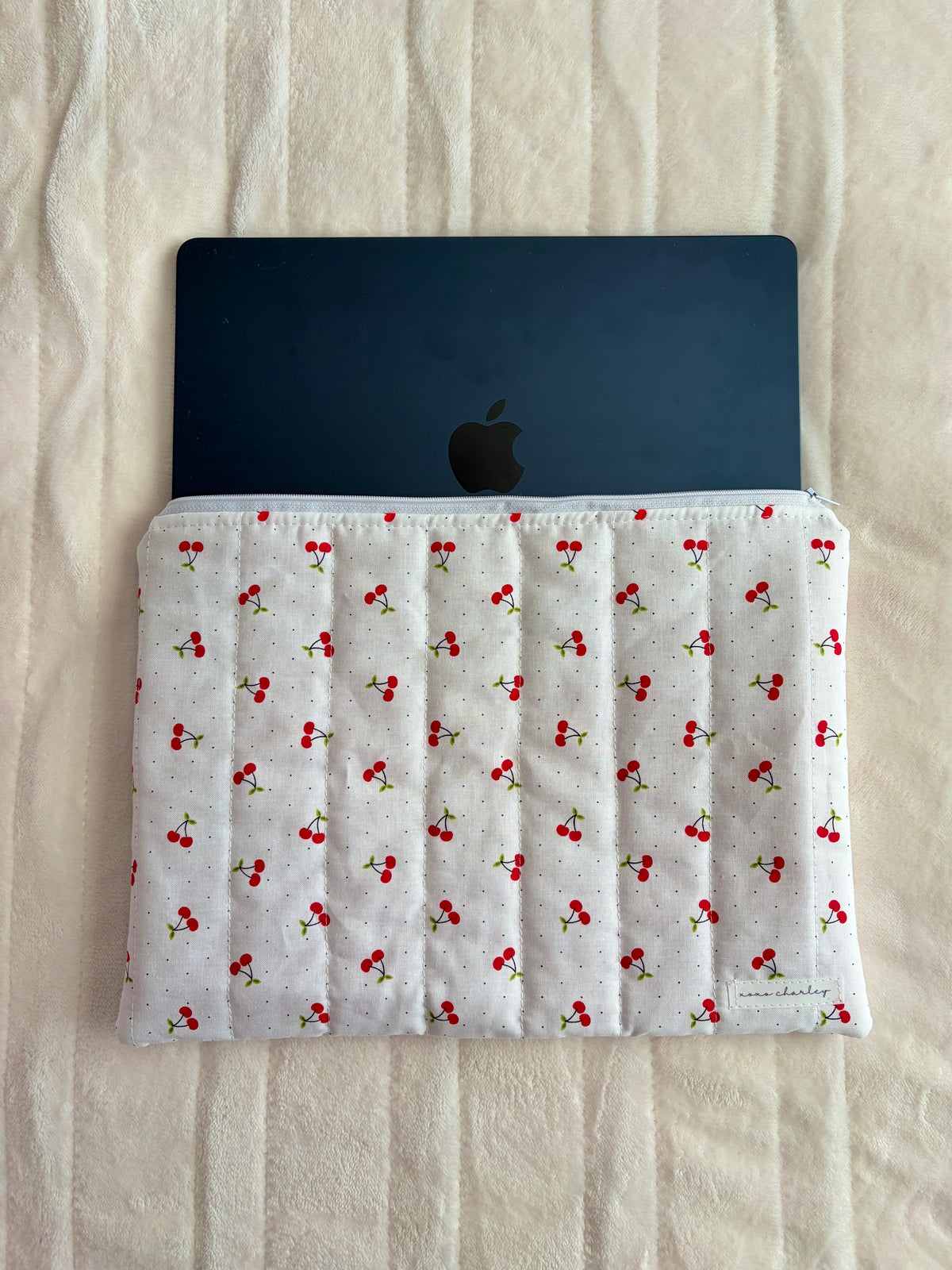 Laptop and tablet sleeve with red cherry print, holding a dark tablet with Apple logo