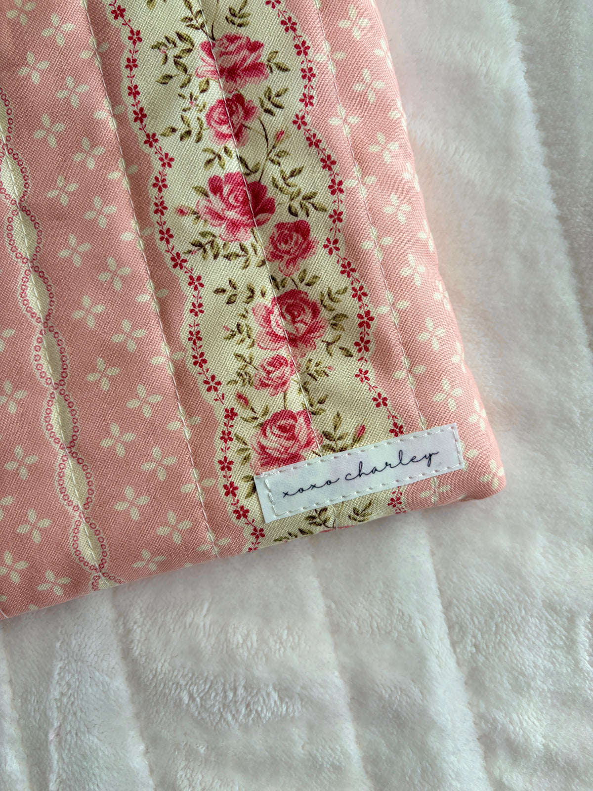 Close-up of pink floral tablet sleeve with fabric tag and striped trim