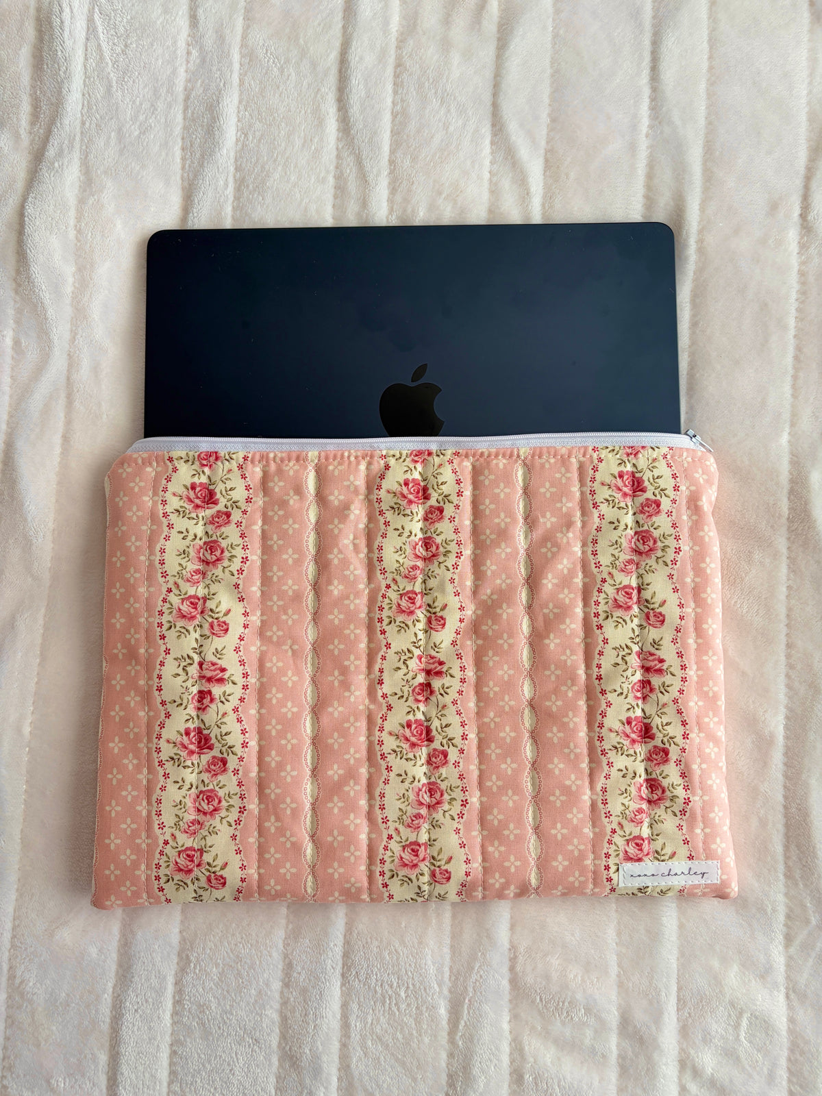 Pink floral laptop sleeve with zipper, holding a black laptop