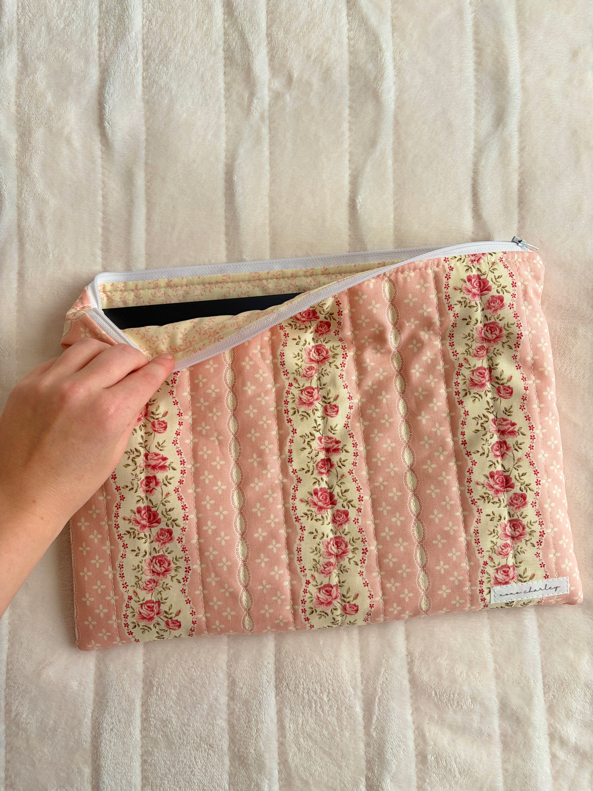 Pink floral laptop sleeve being opened, showing striped interior