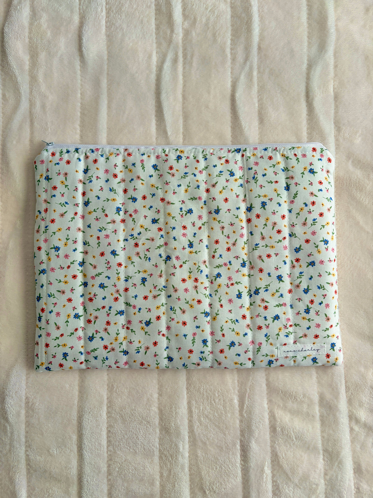 Colorful mini floral laptop sleeve with padded white cover and stitched border.