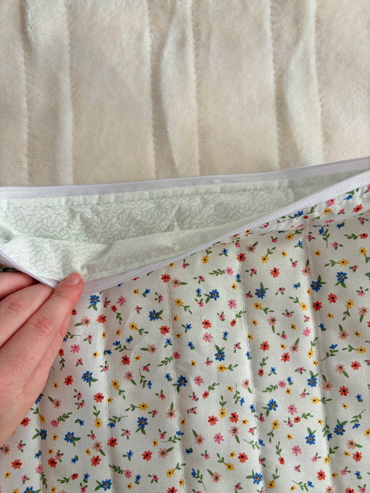 Open floral mini sleeve showing padded light gray interior lining and zipper track.