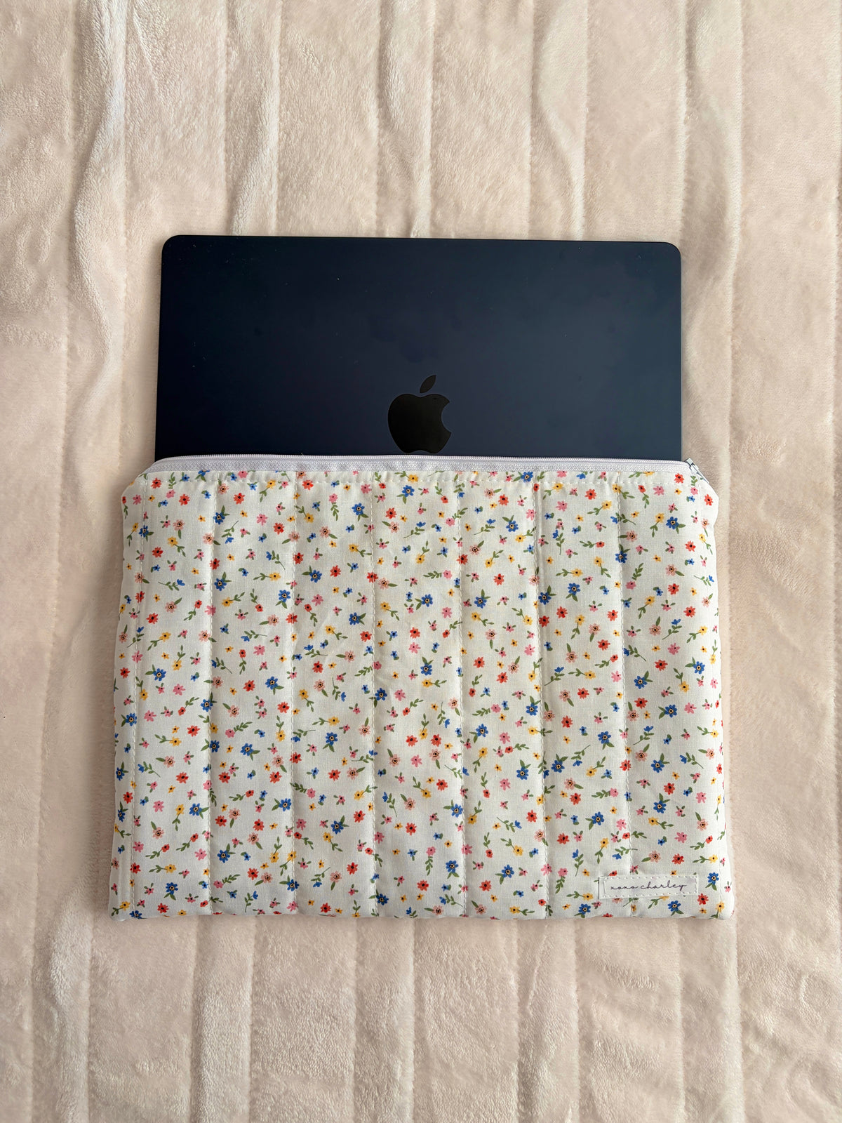 Floral padded laptop sleeve with top rim holding a tablet-sized device.