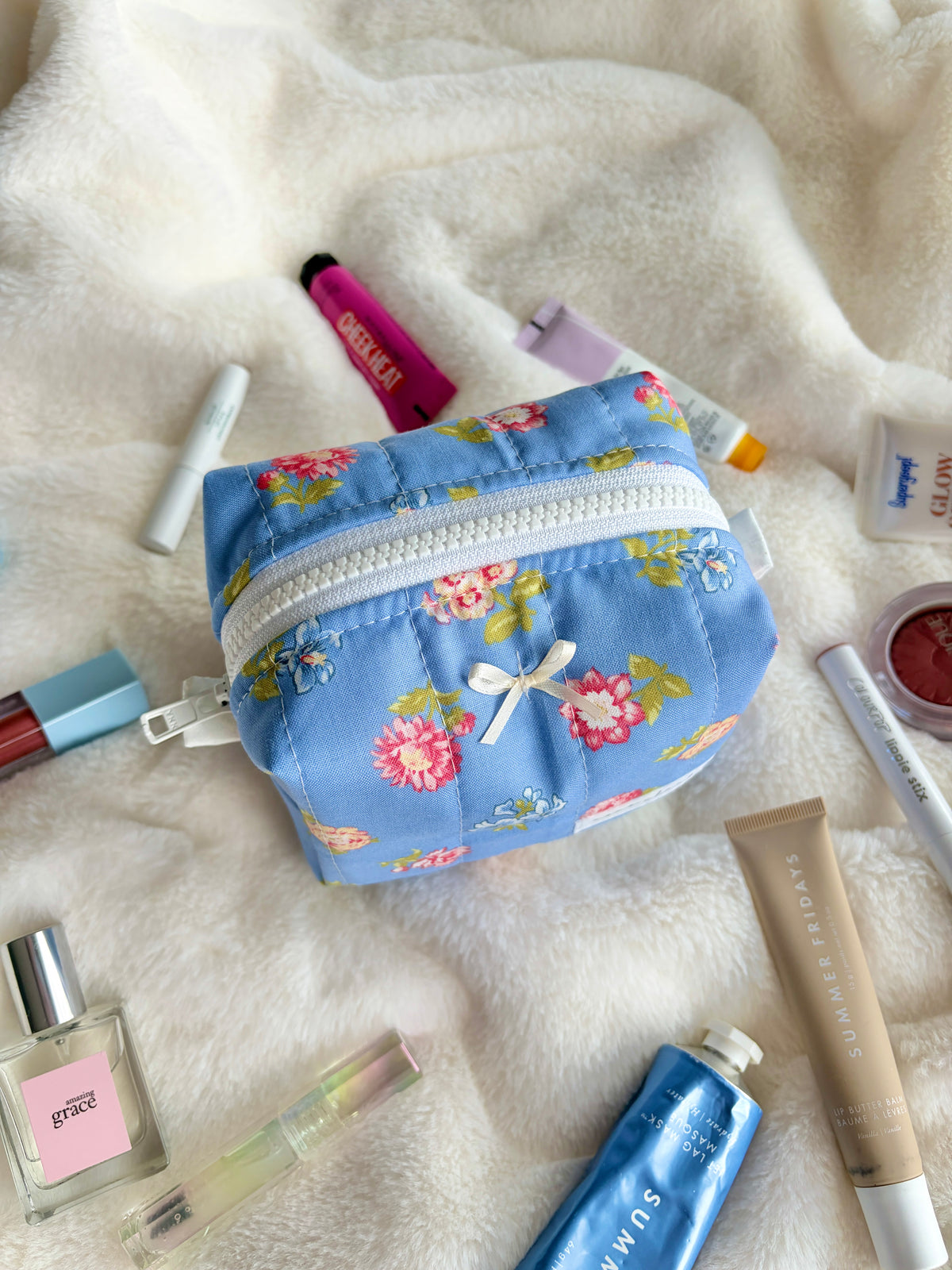 Blue floral mini makeup bag with white zipper trim, angled view