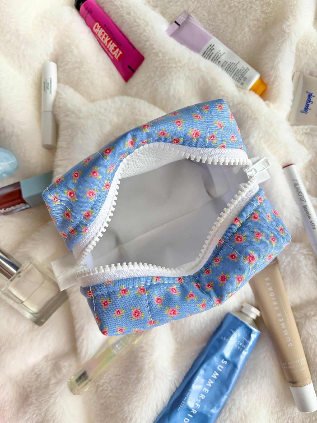 Mini makeup bag opened, showing light gray interior and white zipper trim