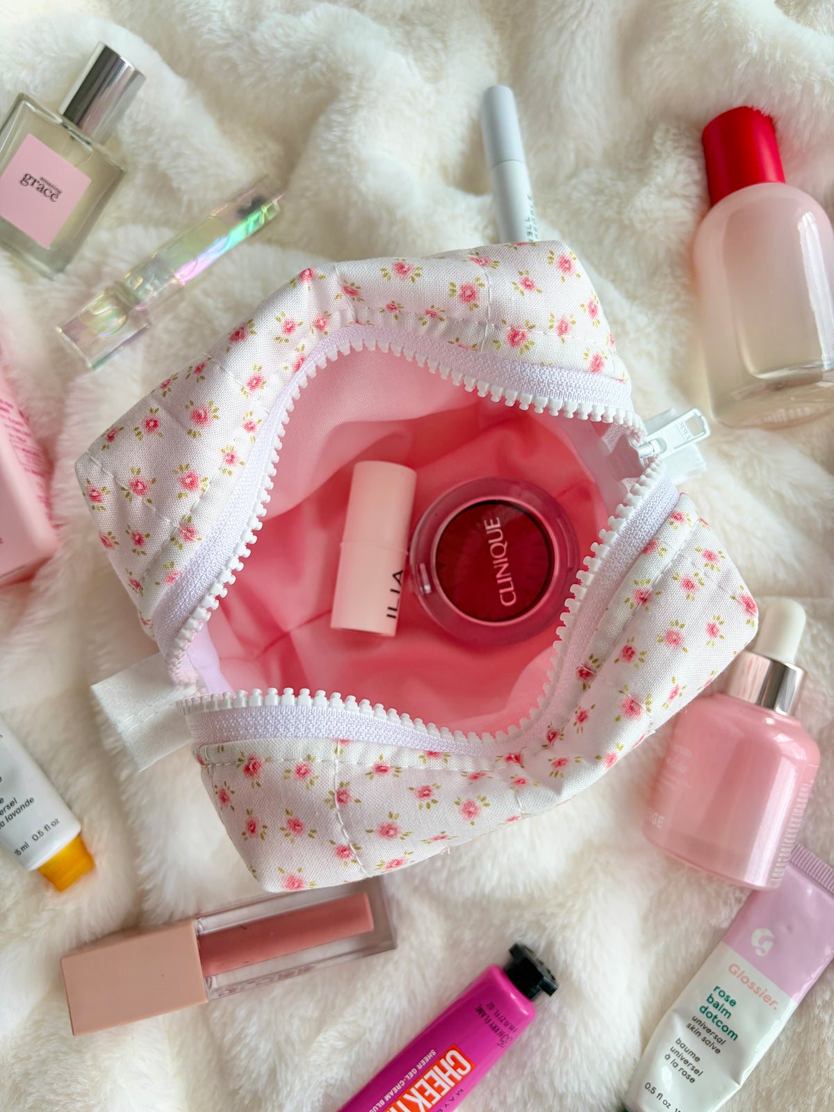 Open mini makeup bag showing pink interior lining with small bottles inside