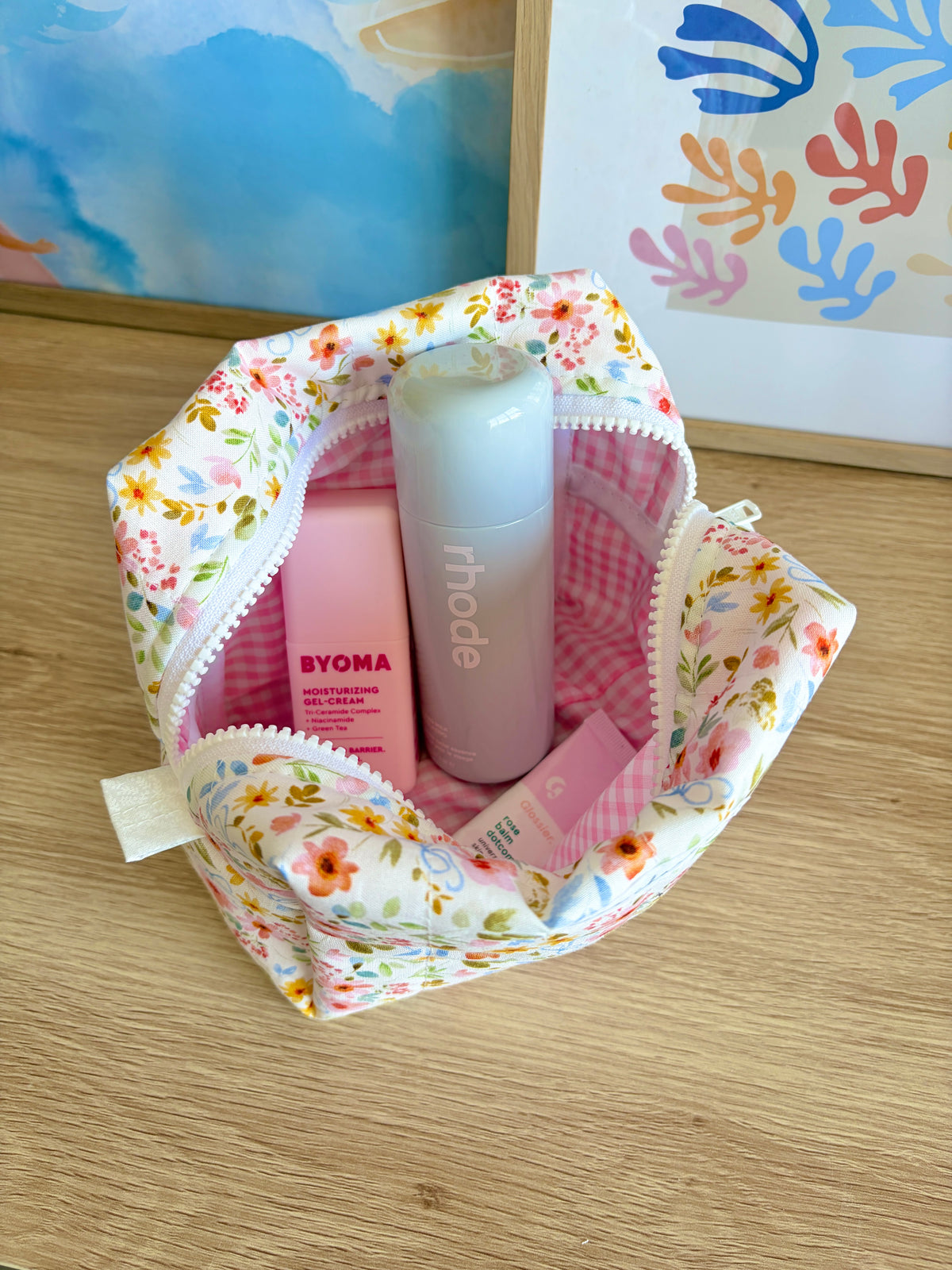 Medium floral makeup bag open with pink gingham lining, white zipper, multicolor flowers.