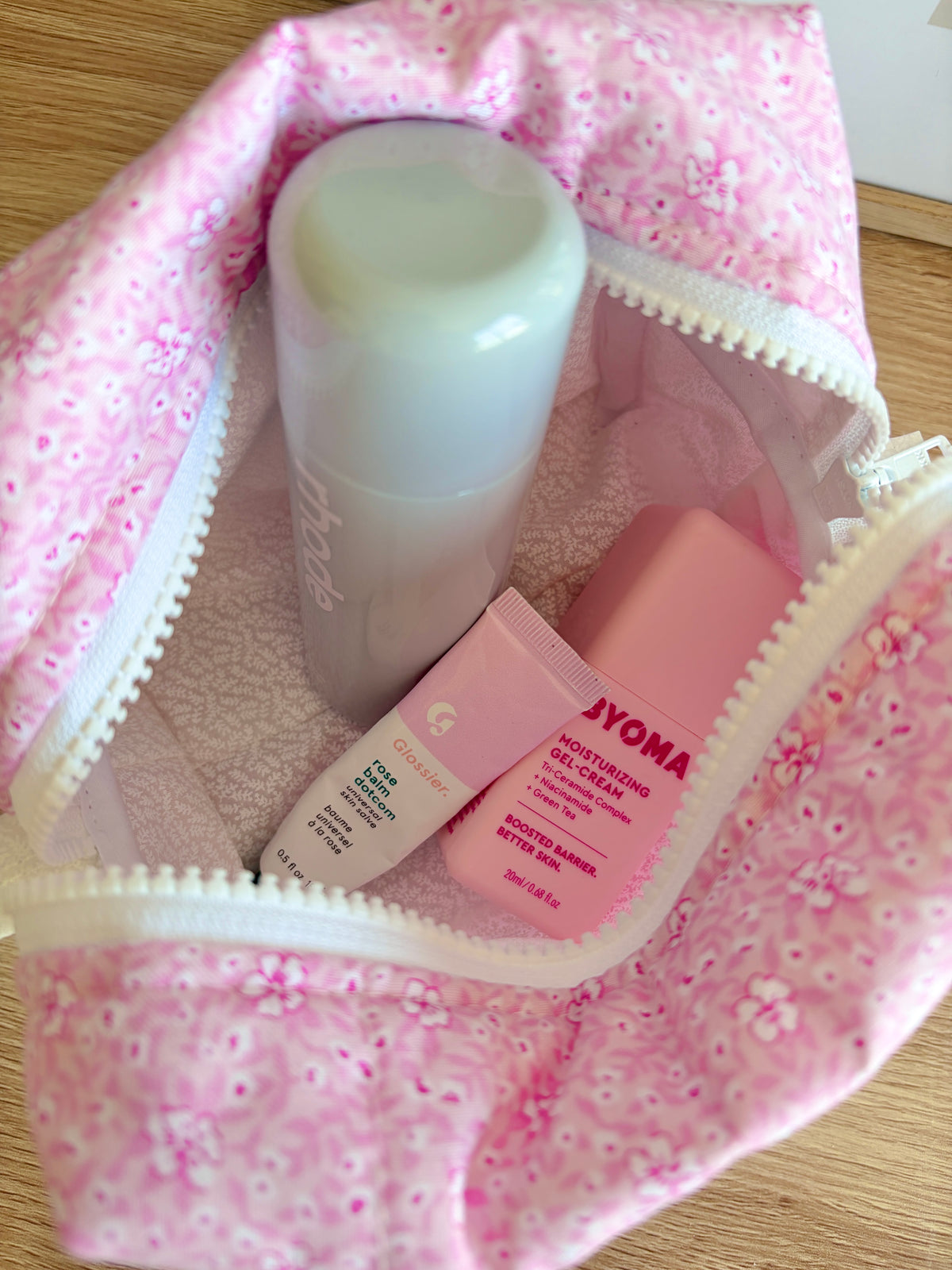 Pink glitter makeup bag interior close-up with zipper trim and skincare items