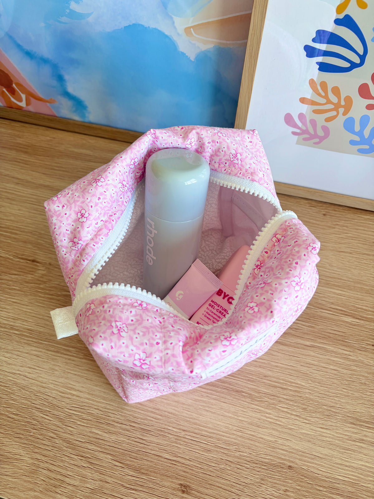 Pink Hawaiian glitter makeup bag with zipper, open to show bottles and labels