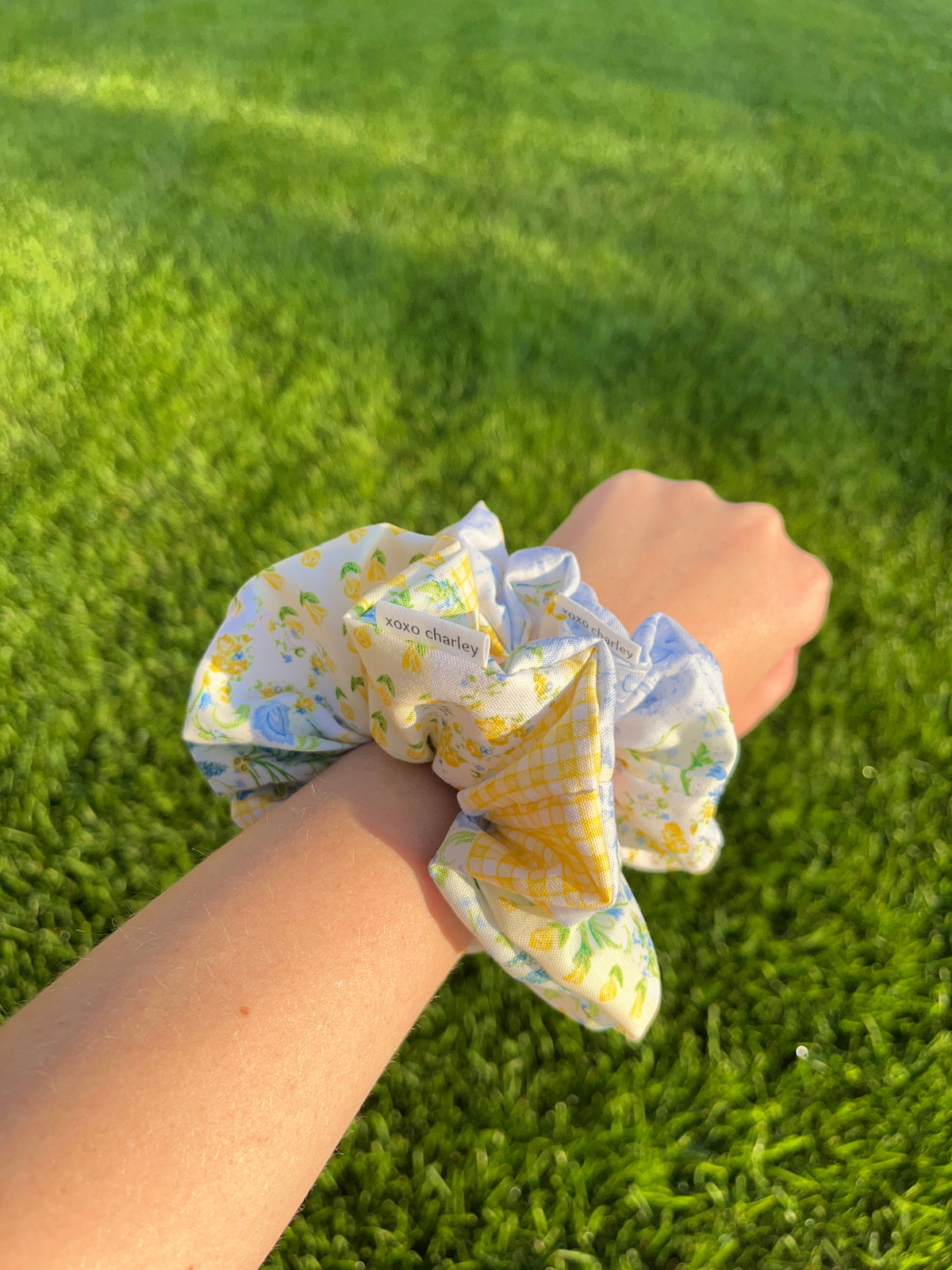 Cotton patchwork scrunchie, light blue and yellow with green accents, on wrist.