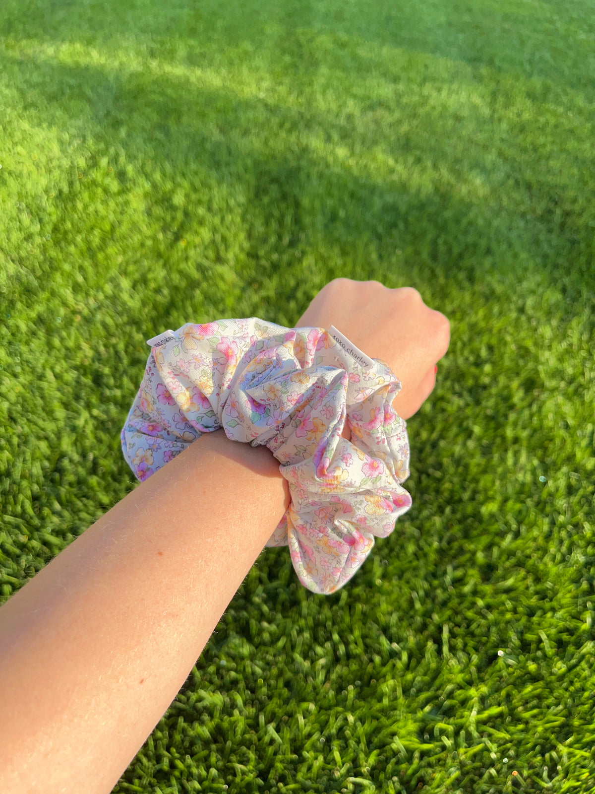 Cotton scrunchie, pastel floral print gathered elastic band on wrist.