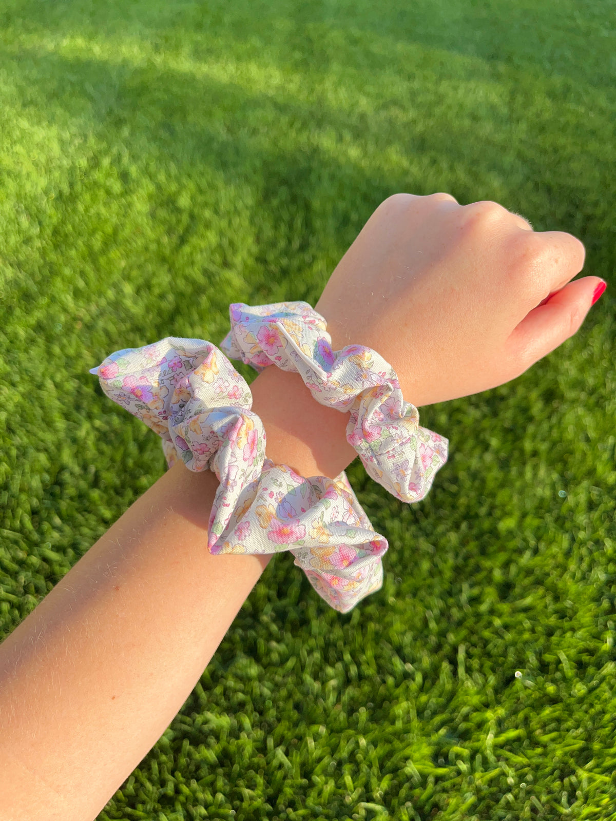 Cotton scrunchie with pastel floral print, scrunched elastic on wrist.