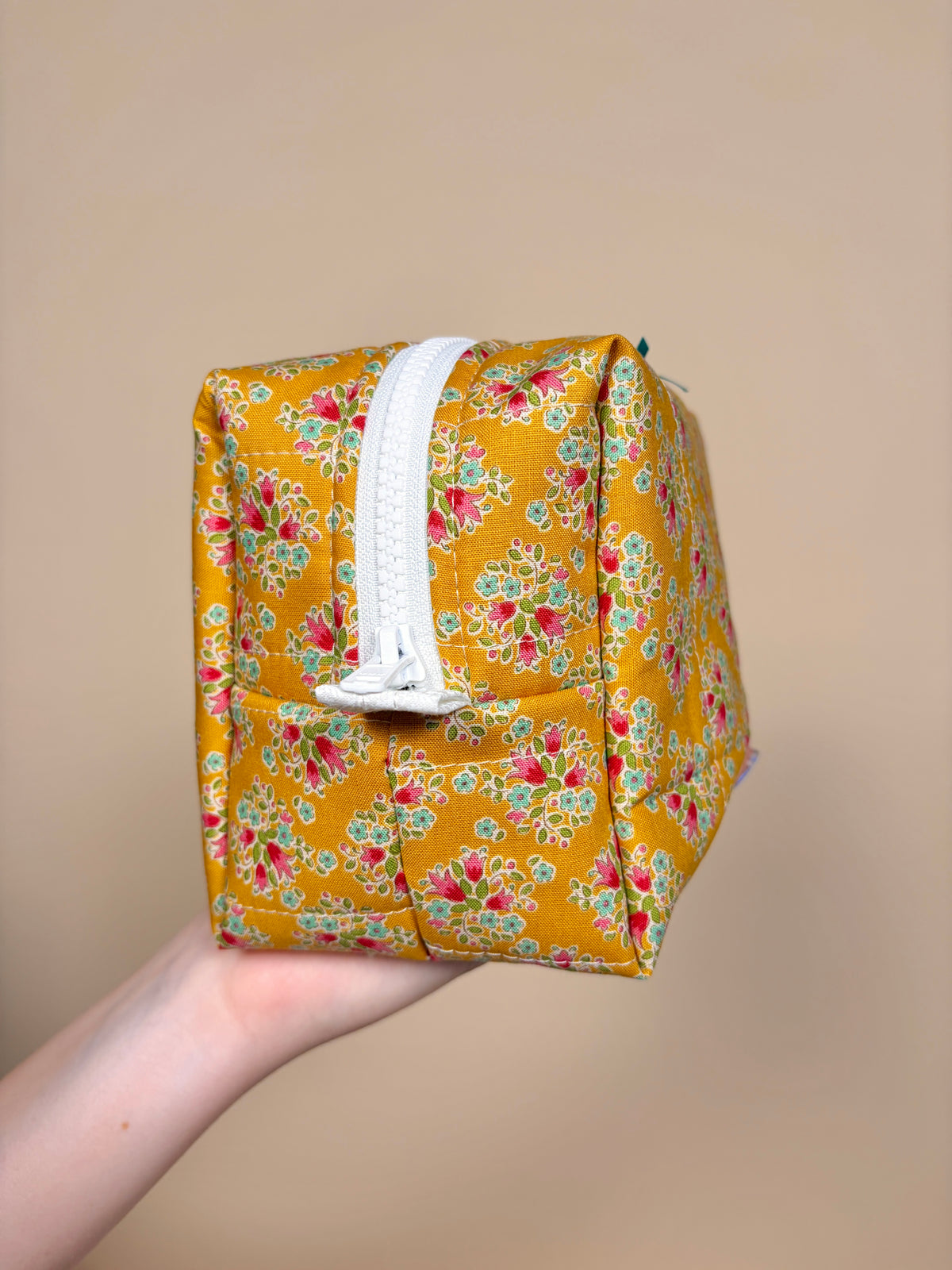 Floral bow makeup bag with white zipper trim and folded handle detail