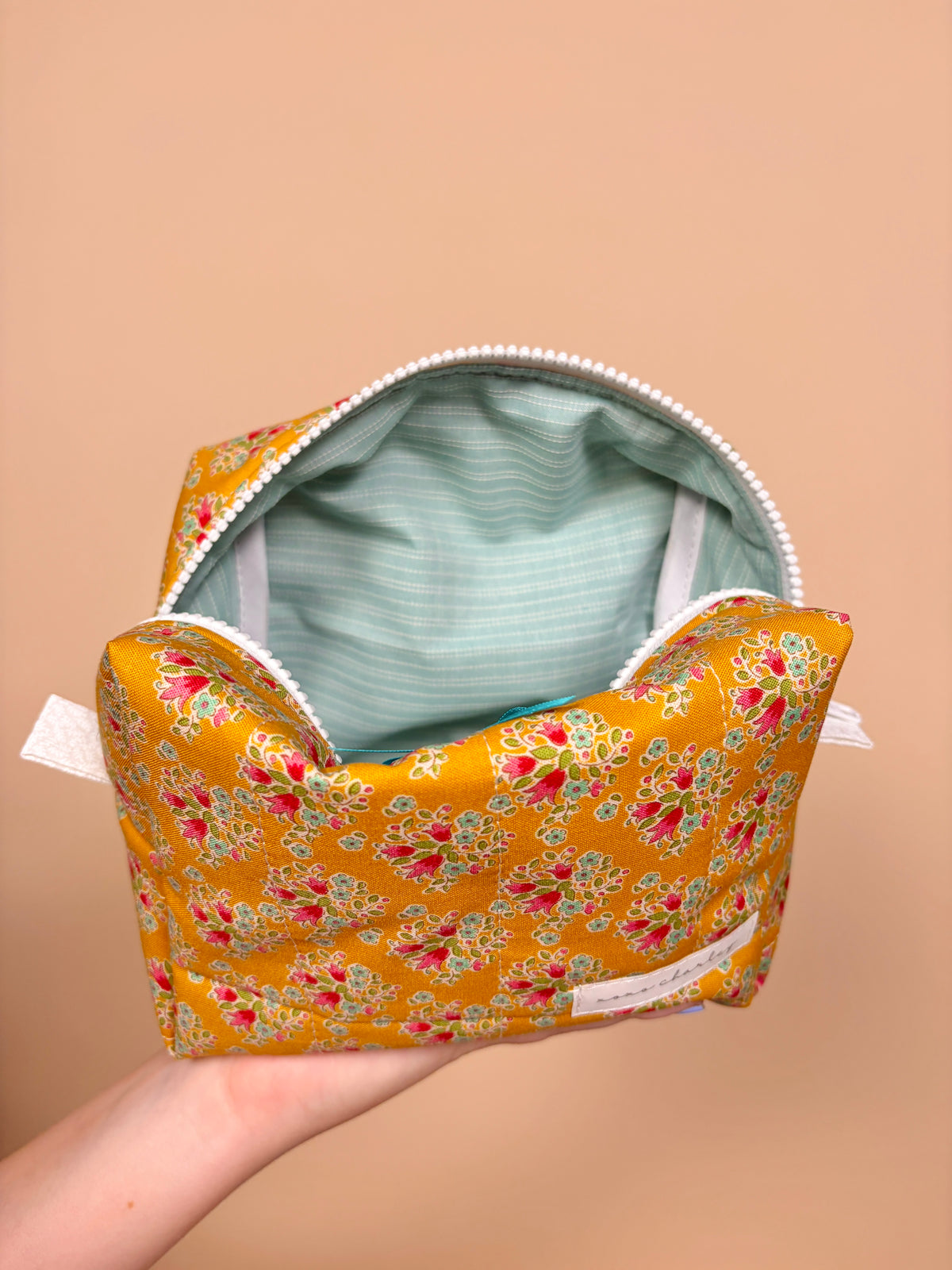 Open floral bow makeup bag with light gray striped lining and zippered top