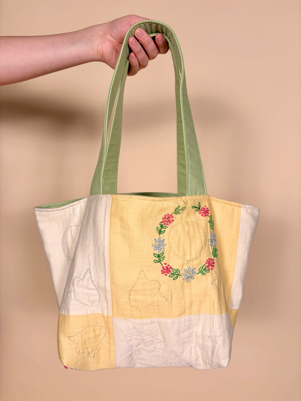 Mini tote bag with white and pale yellow patchwork, floral wreath front, green trim