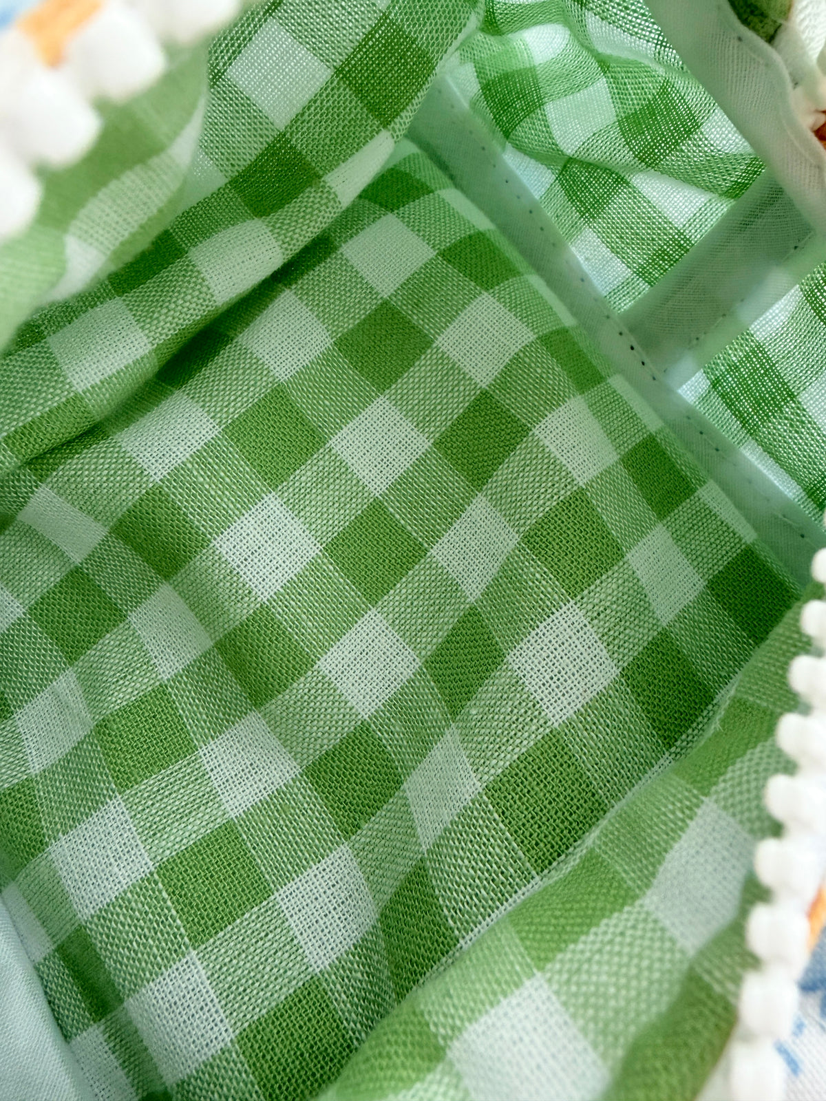 Green gingham lining fabric with white pom-edged zipper trim detail