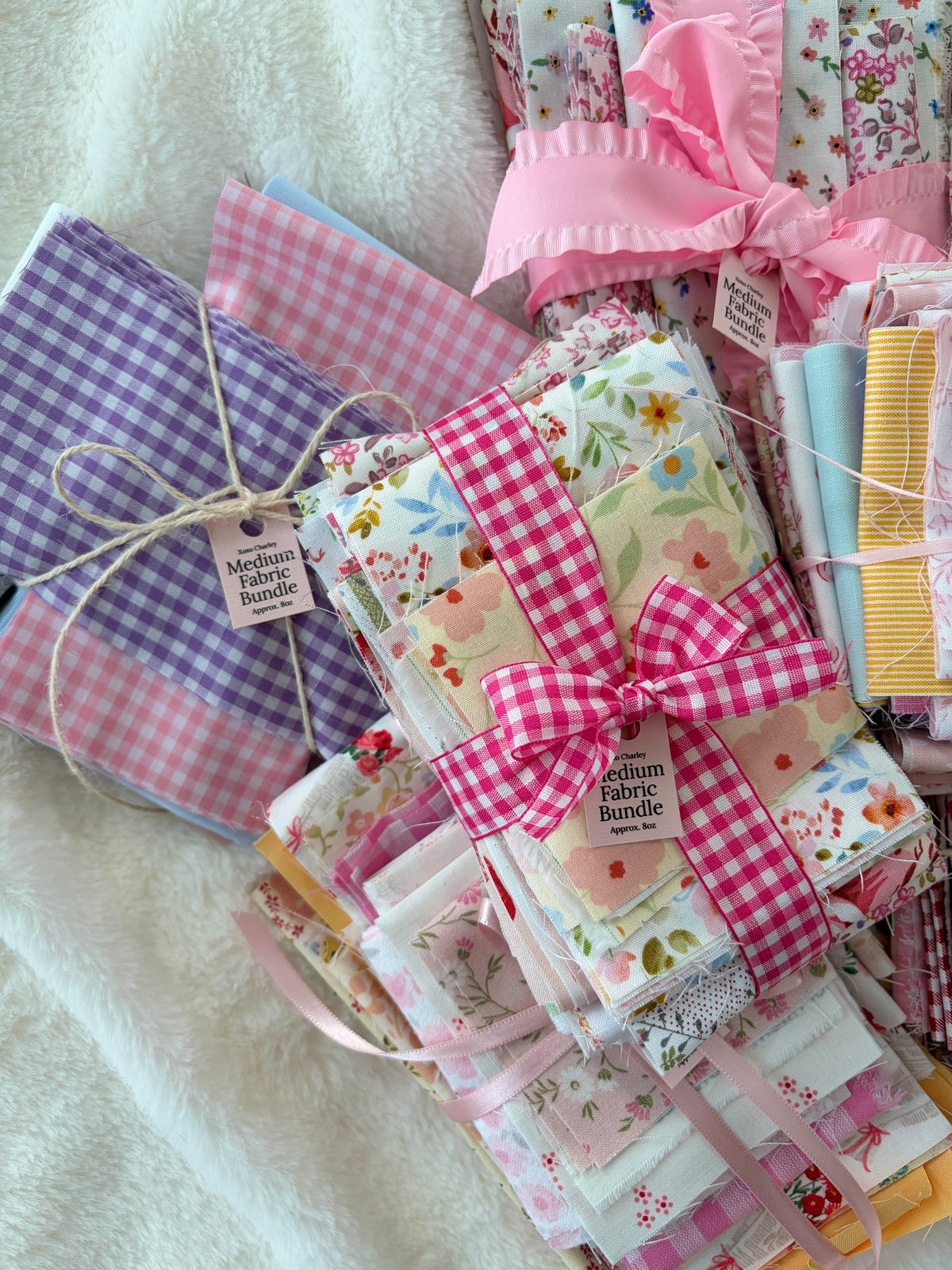 Folded pastel fabrics with pink gingham and small floral prints, ribbon-tied bundle