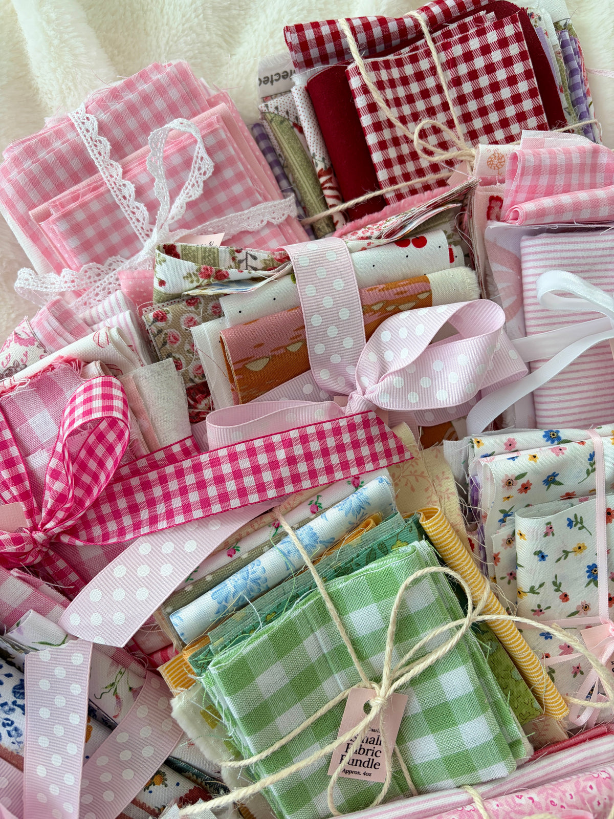 Assorted fabric bundle with pink lace-trimmed stacks and green plaid fabric squares