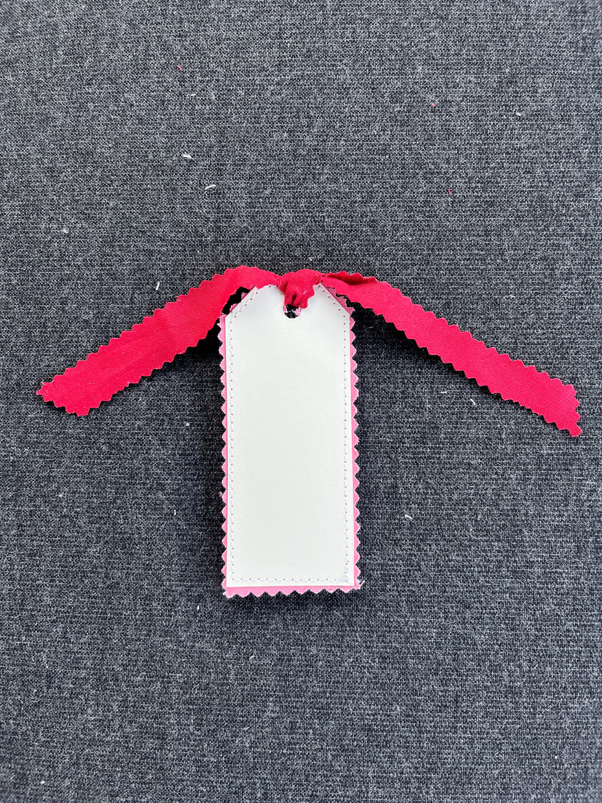 White gift tag with strawberry pattern and maroon ribbon, stitched border