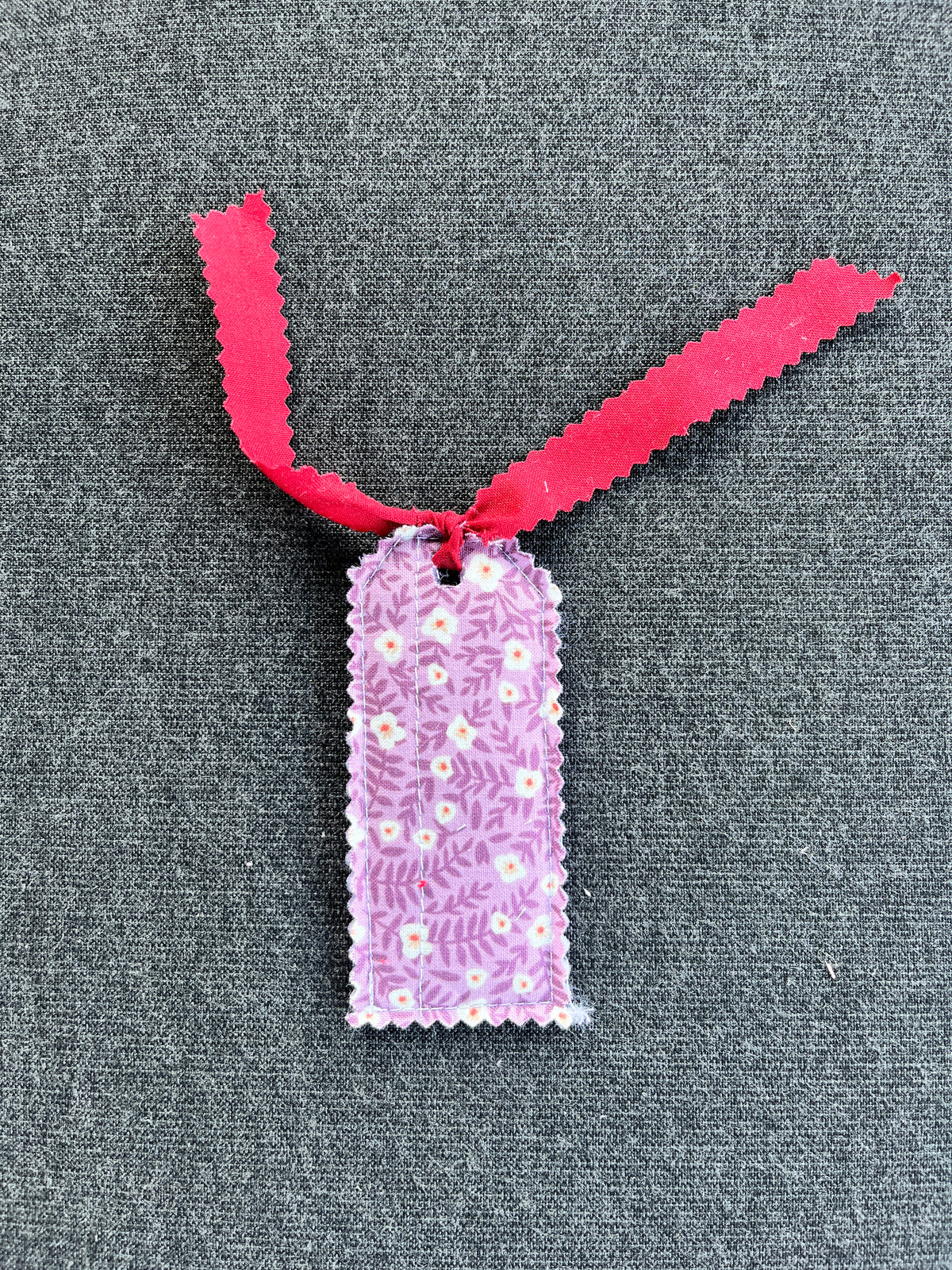 Floral gift tag with pink ribbon and textured purple-pink pattern
