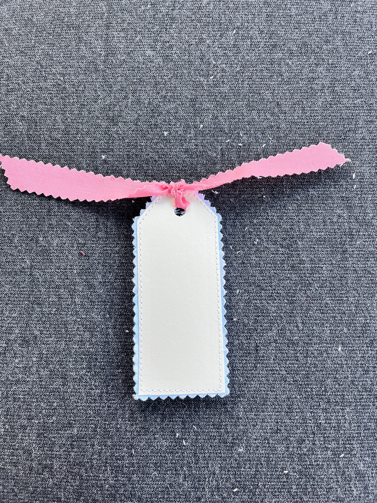 White gift tag panel with blue border and blush pink bunny-ear top with ribbon