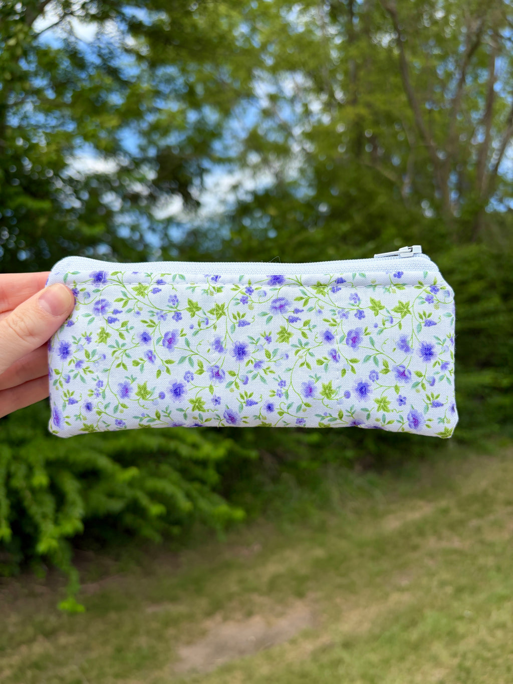 Zippered glasses case with purple floral print, green gingham trim, and stitched seams.