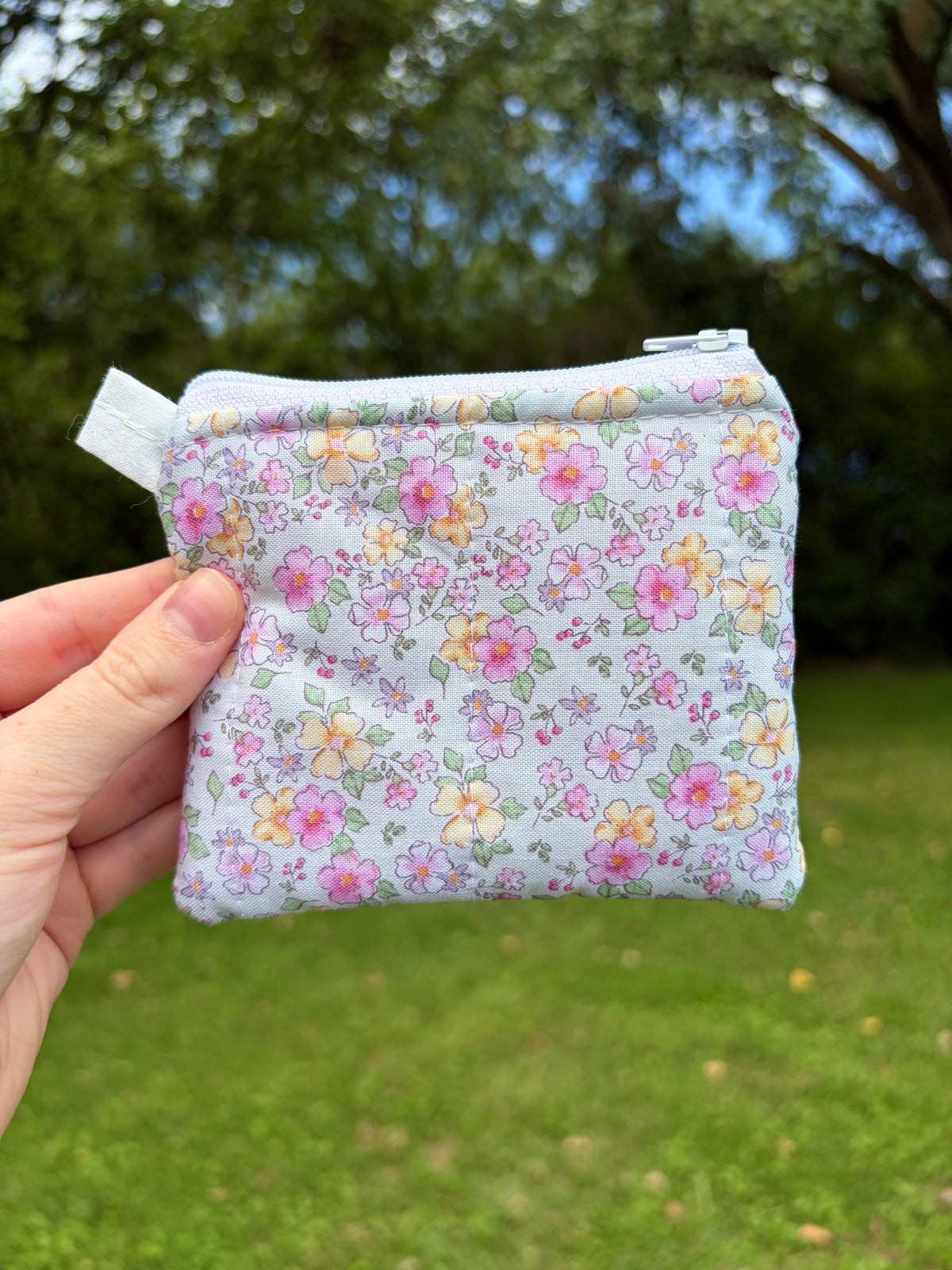 Pastel floral zip-top keychain wallet with fabric loop, rounded shape, all-over print.