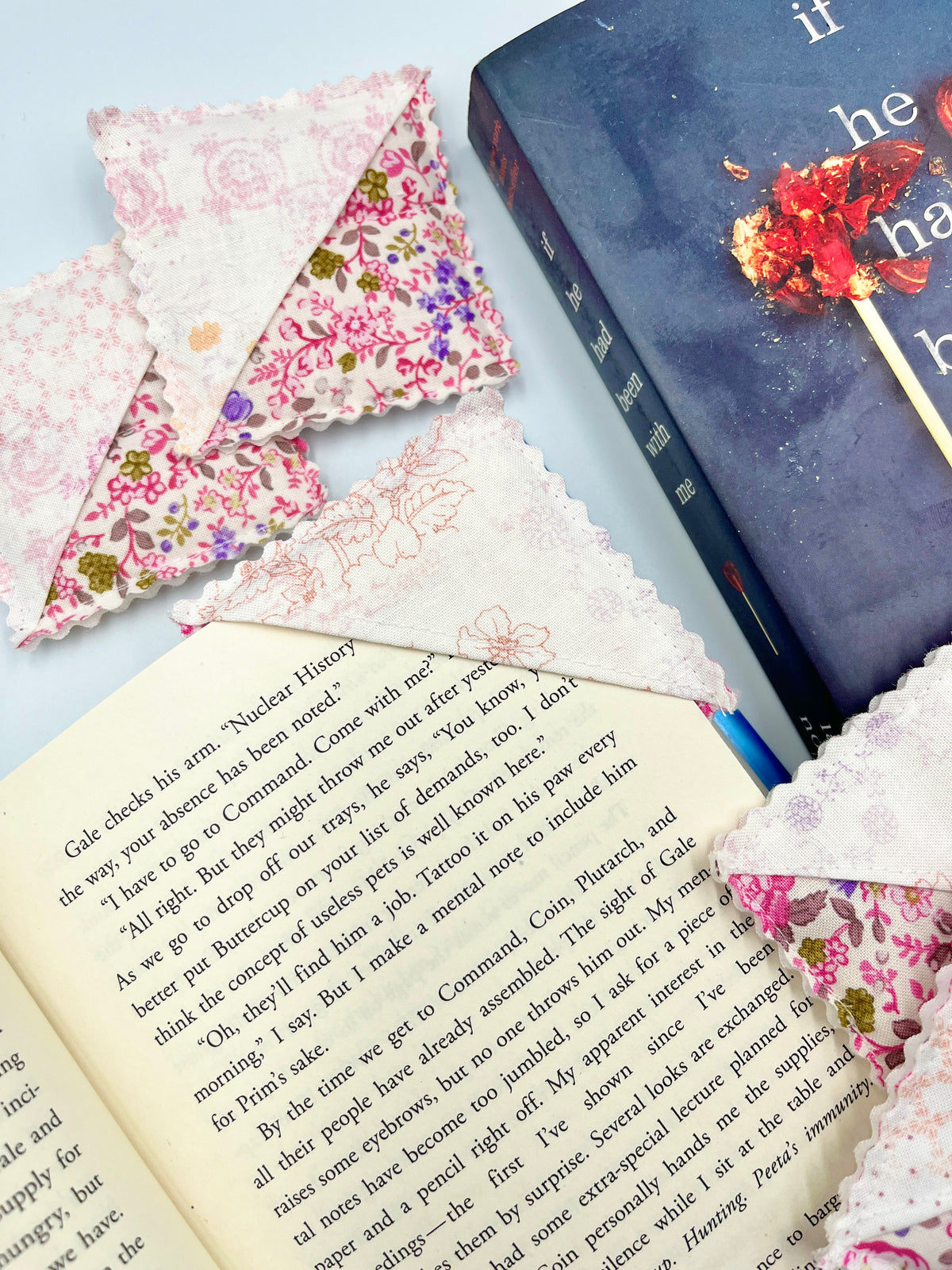 Pink floral fabric corner bookmark with pointed corners and scalloped trim on a book