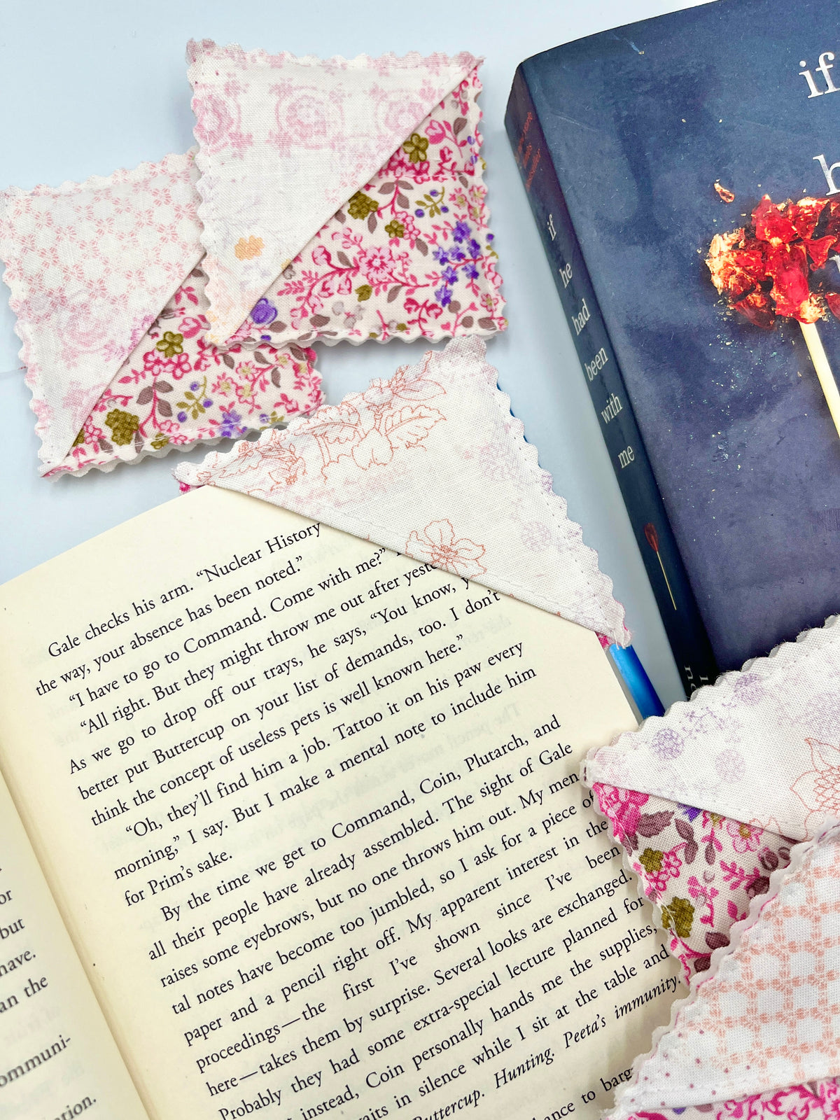 Pink patterned fabric corner bookmark with scalloped edge on an open book page