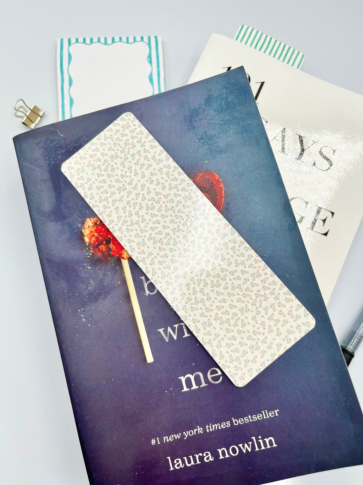Mini floral bookmark, cream with tiny multicolor flowers, angled on an open book