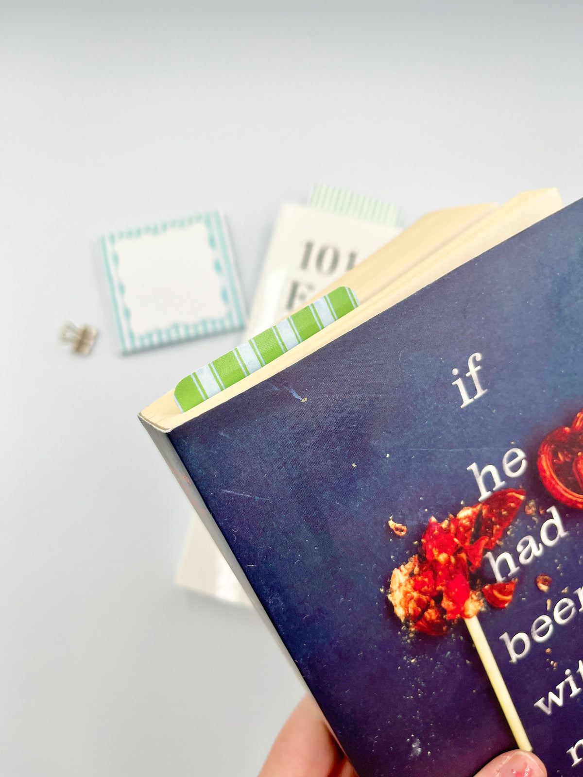 Green and white striped bookmark held over a book page