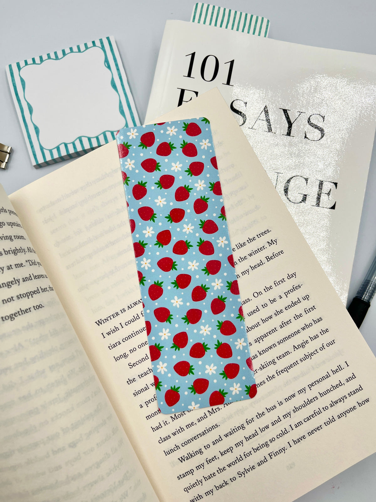 Strawberry-pattern fabric bookmark with wooden stick, placed on an open book