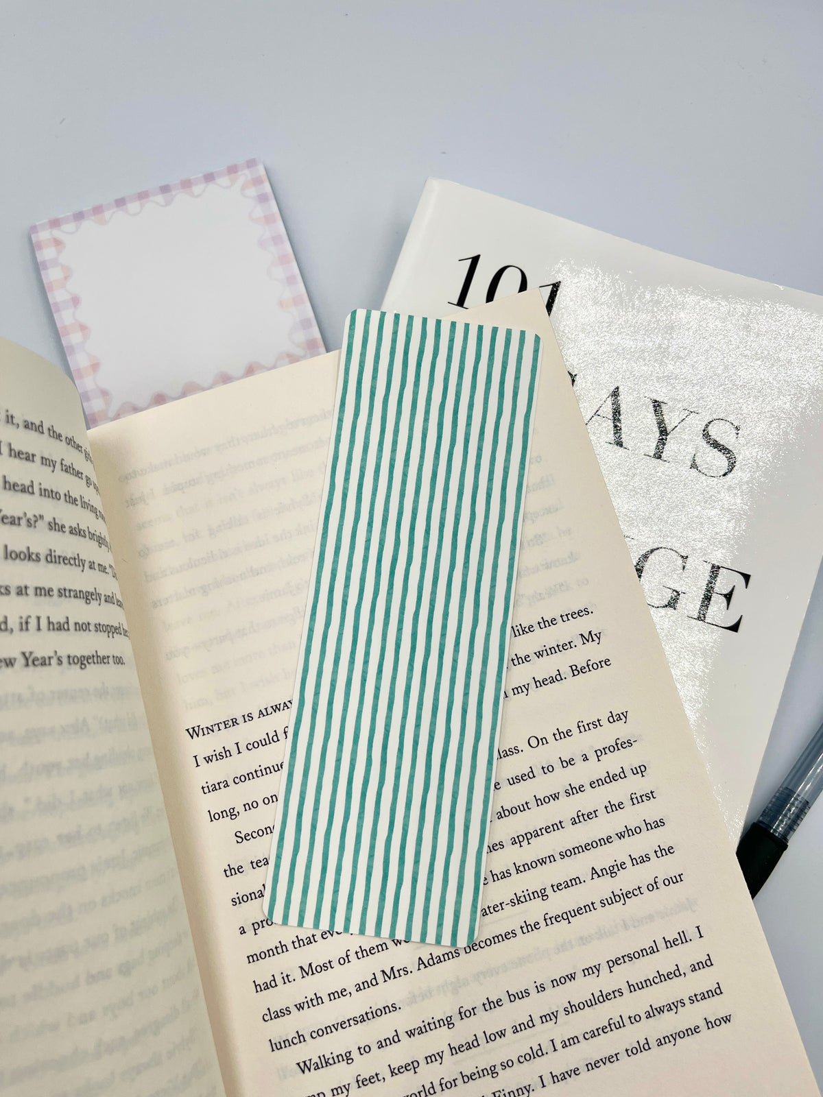 Teal striped bookmark with vertical white stripes, placed between open books