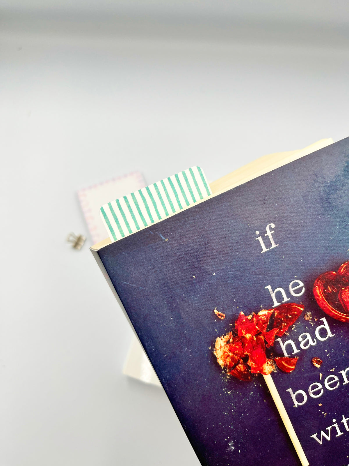 Teal striped bookmark tucked in a dark book, vertical white stripes