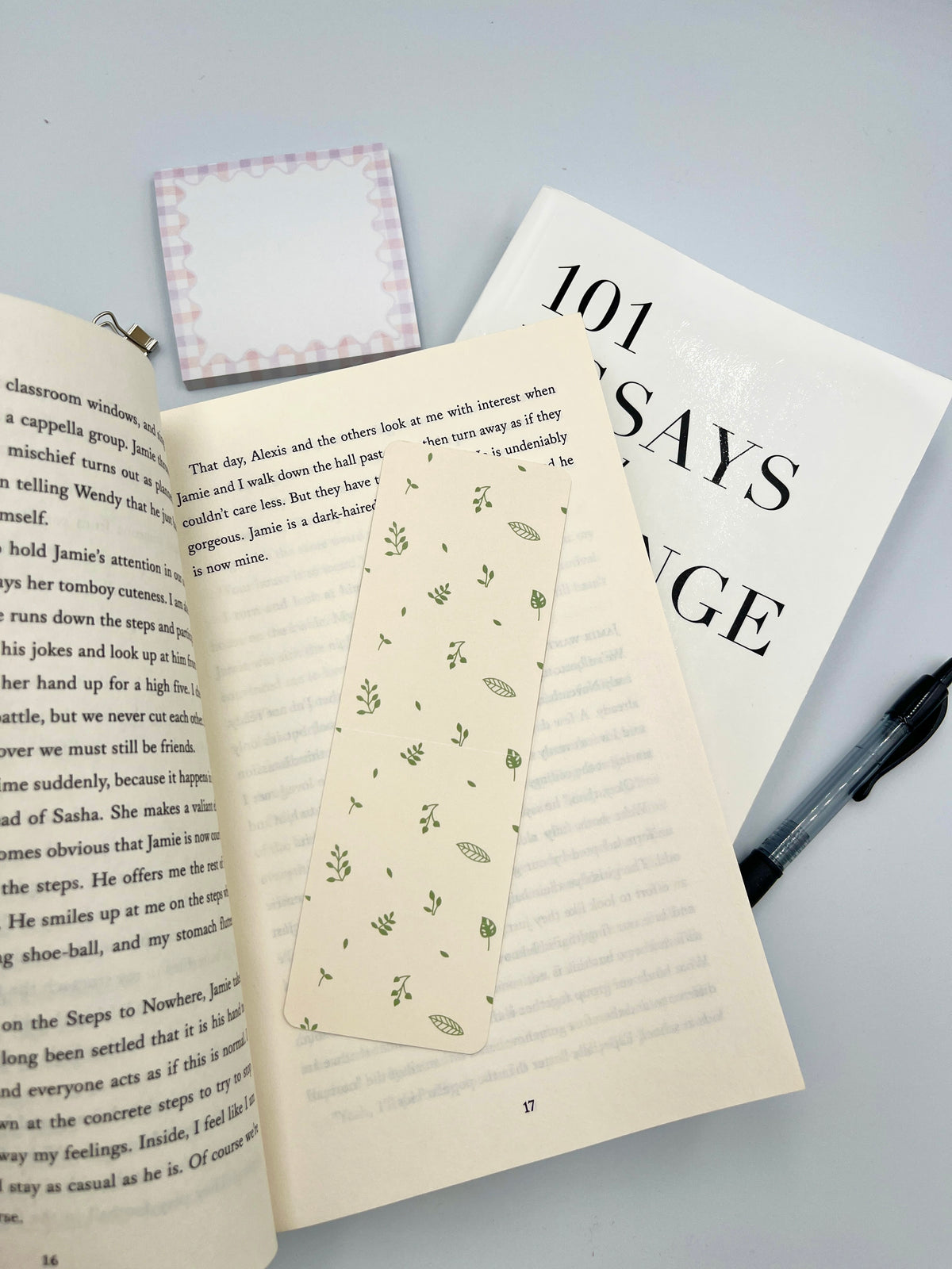 Cream bookmark with green leaf pattern, shown between open books.