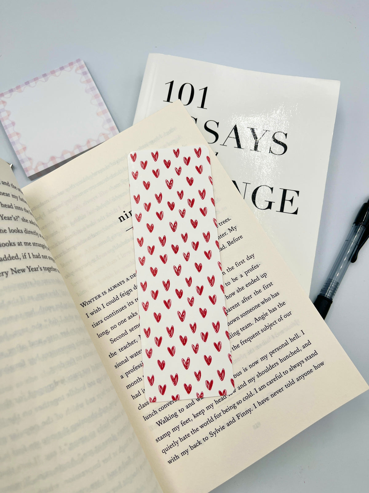 Red heart patterned fabric bookmark on white paper, pointed top