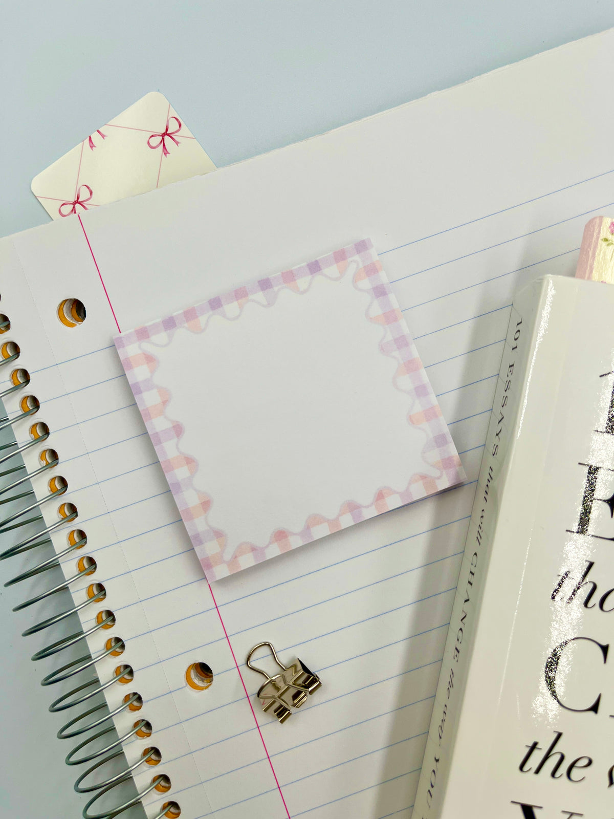 Pastel gingham sticky note square with pink border on lined notebook
