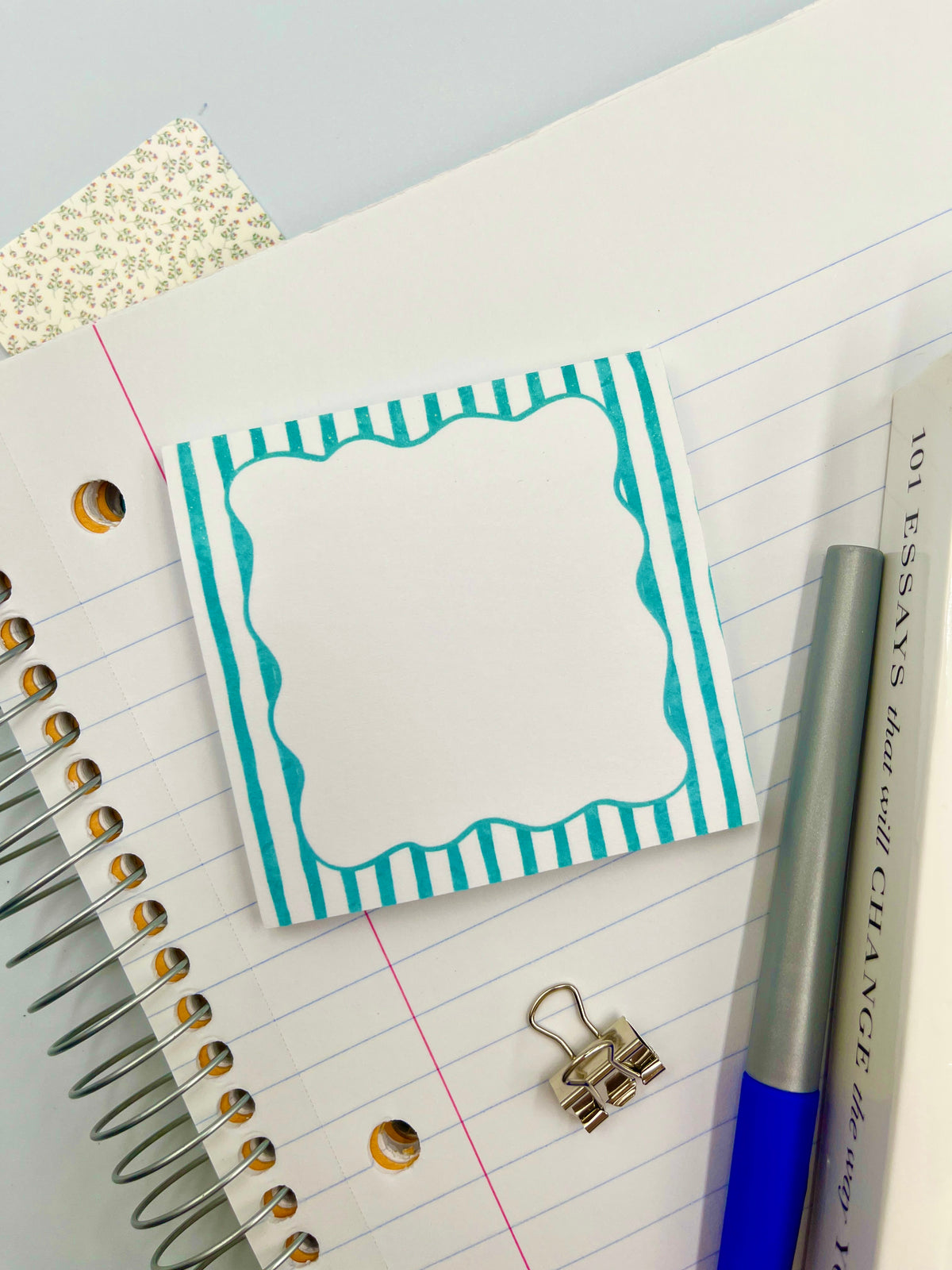 Teal striped square sticky note with blank page on a lined notebook