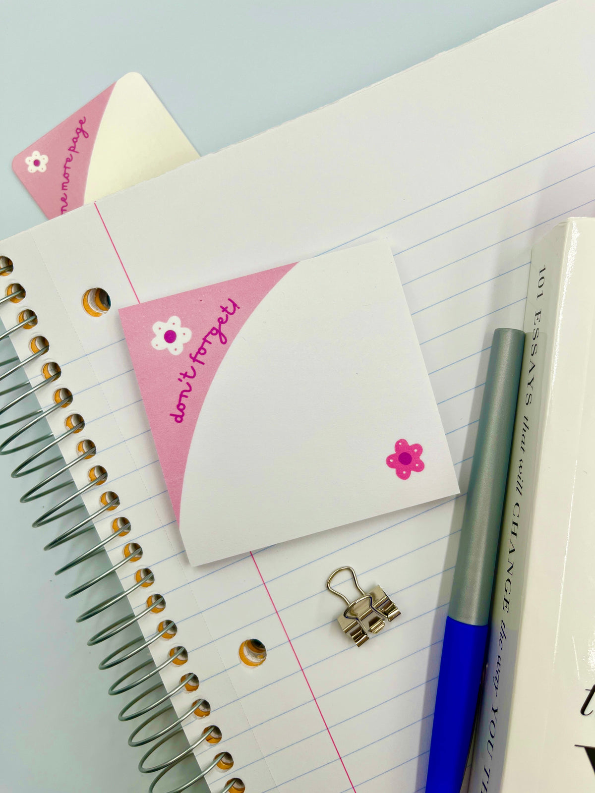 White sticky notes with pink flower accents and a pink border, on lined paper