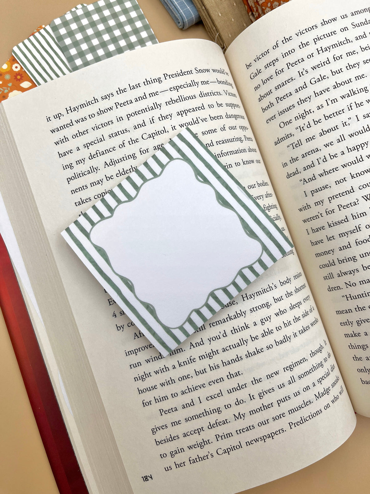 Green striped sticky note label on open book page, with other note tabs nearby