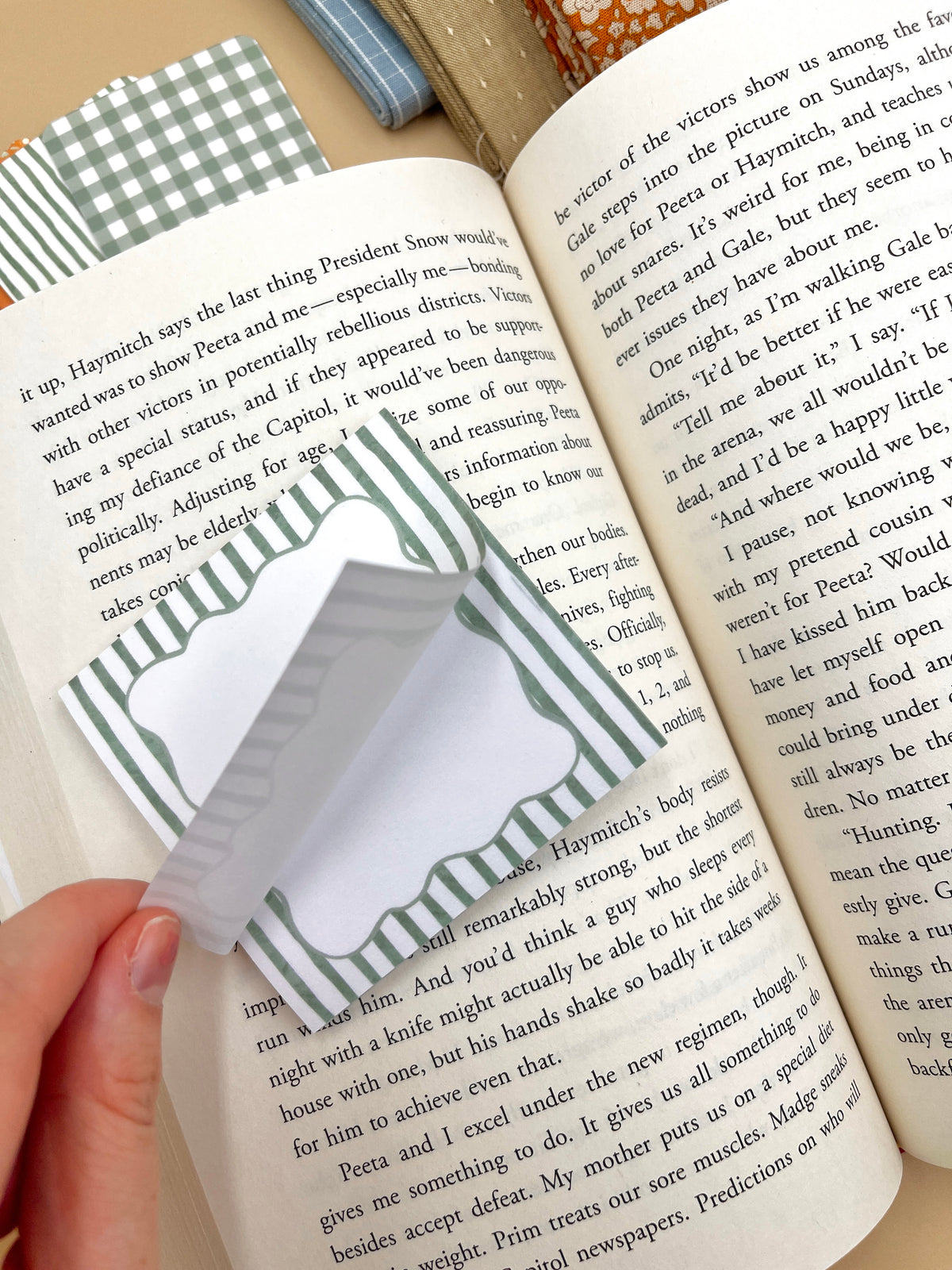Hand holding a green striped label sticky note over an open book page